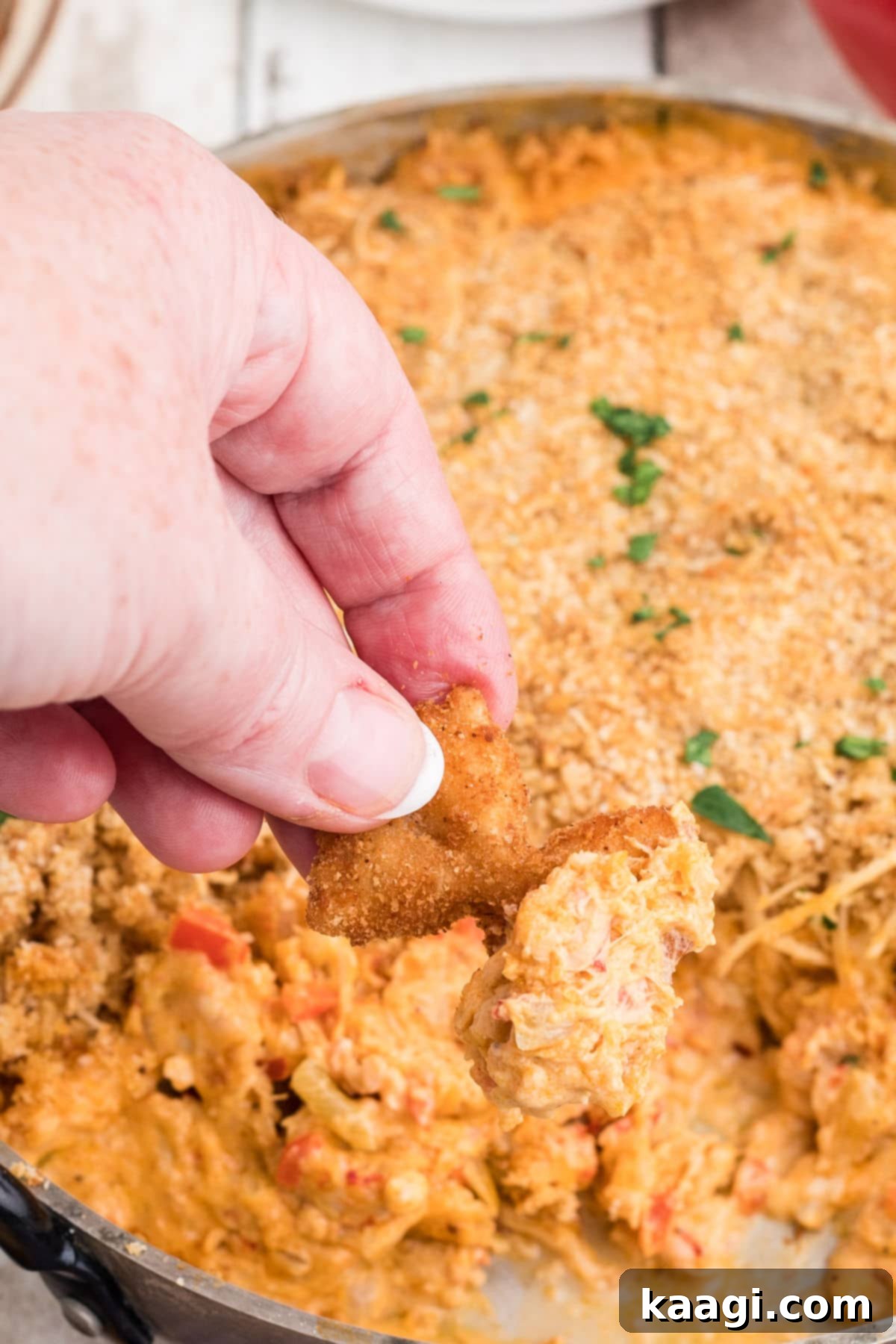 Crispy Farfalle Bites 11 A fried bowtie pasta piece being dipped into a rich, creamy dip, with a hint of melted cheese, showcasing its perfect pairing.