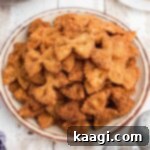 Crispy Farfalle Bites 13 A side view of a plate full of crispy fried bowtie pasta, showcasing its golden brown texture and appetizing appeal.