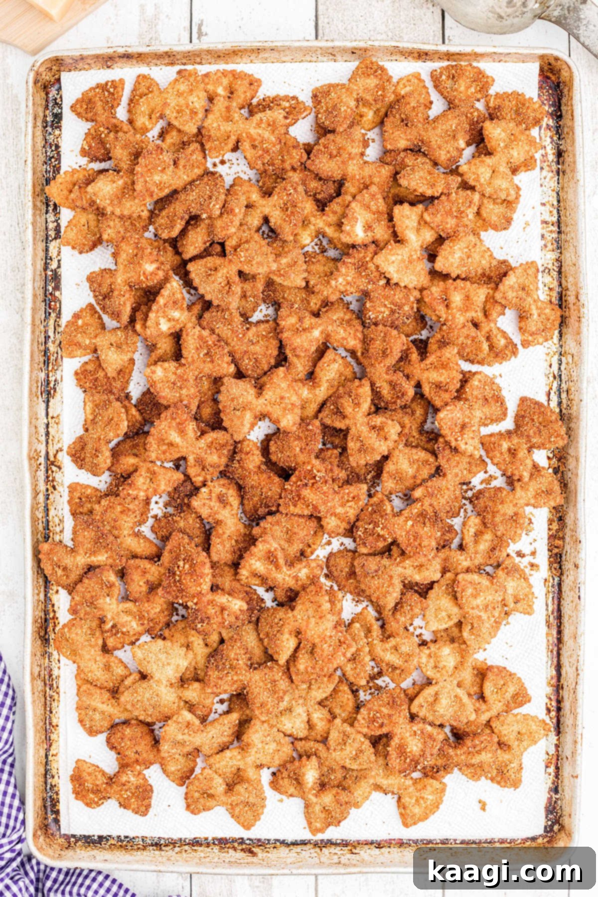 Crispy Farfalle Bites 10 Freshly fried bowtie pasta draining on a baking sheet lined with paper towels, ready to be served.