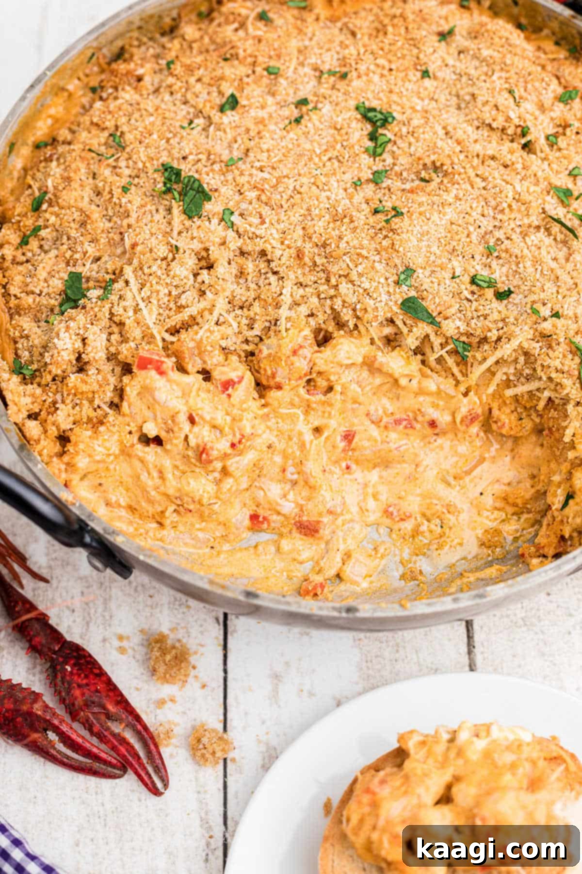 large skillet full of crawfish dip with breadcrumbs on the top, a very cheesy dip. with boiled crawfish in the corners.
