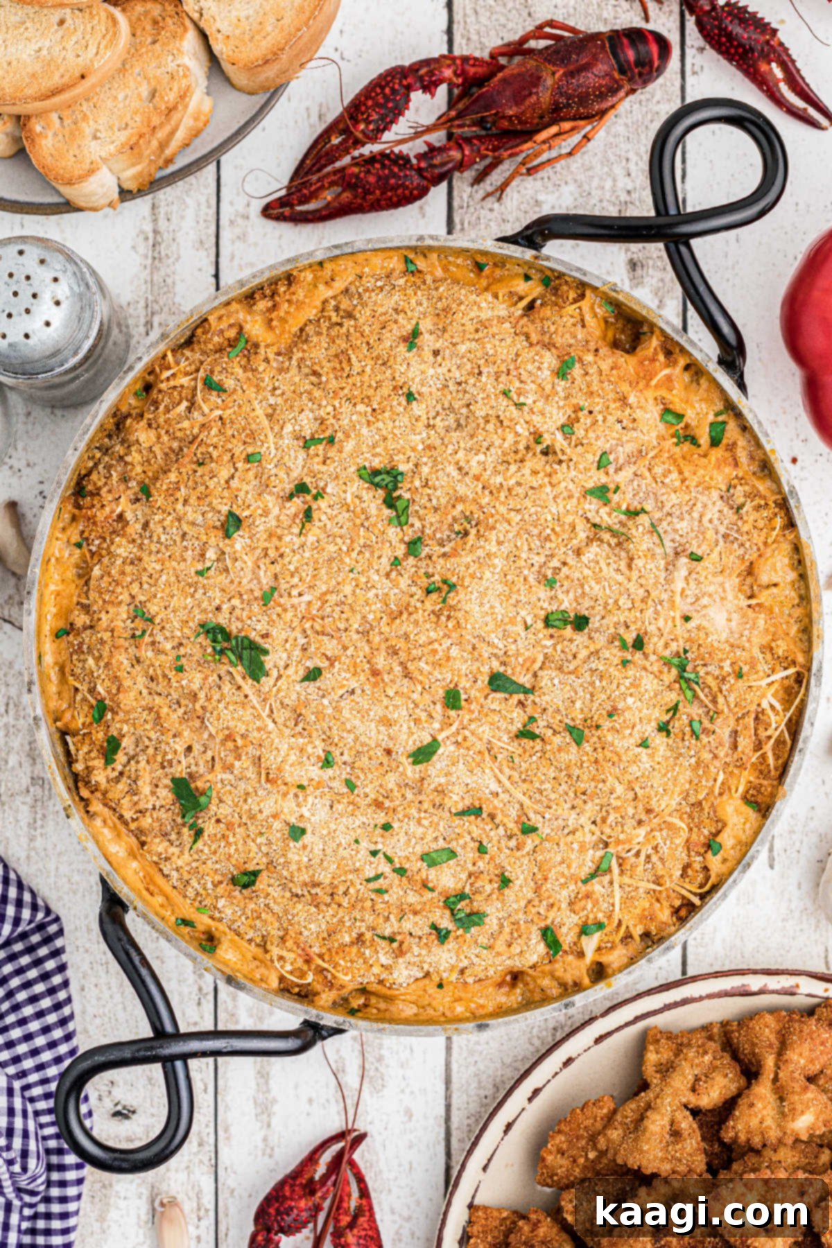 A baked crawfish dip with chopped parsley sprinkled on top.