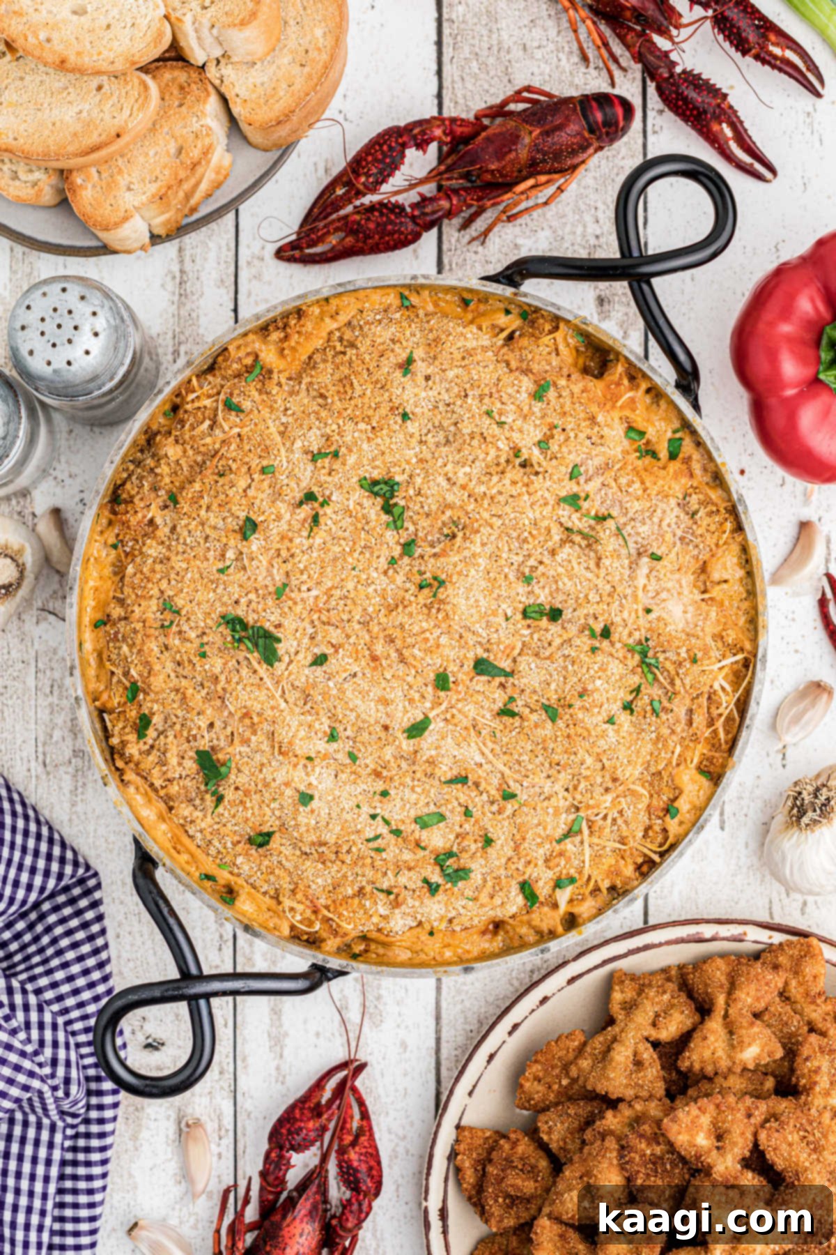 overhead picture of crawfish dip topped with breadcrumbs and cheese with fried bowtie pasta and toasted bread in the corners