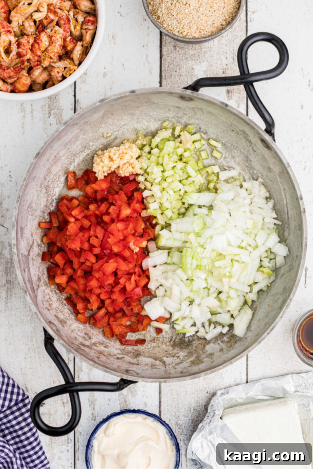 A skillet filled with onions, peppers, celery and garlic.