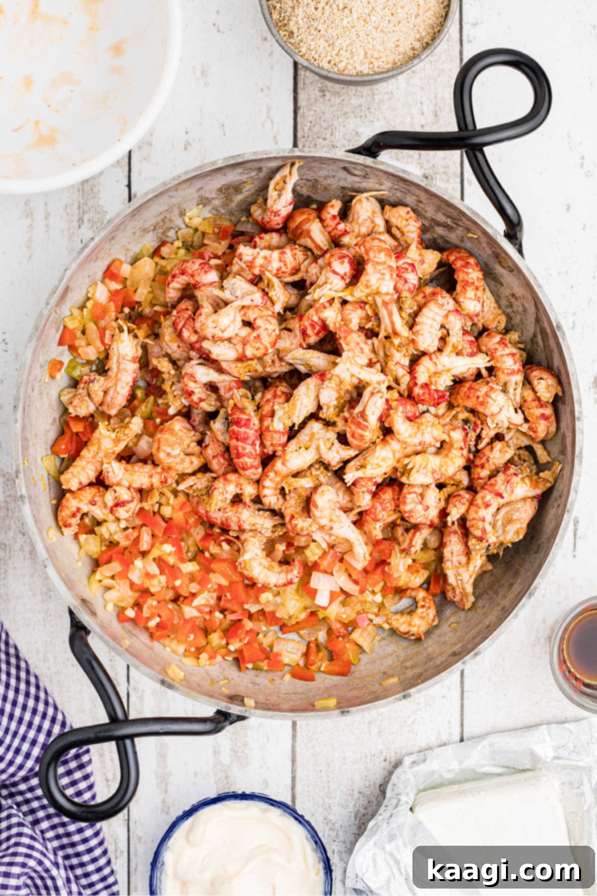 Peeled crawfish tails in a skillet added to veggies.