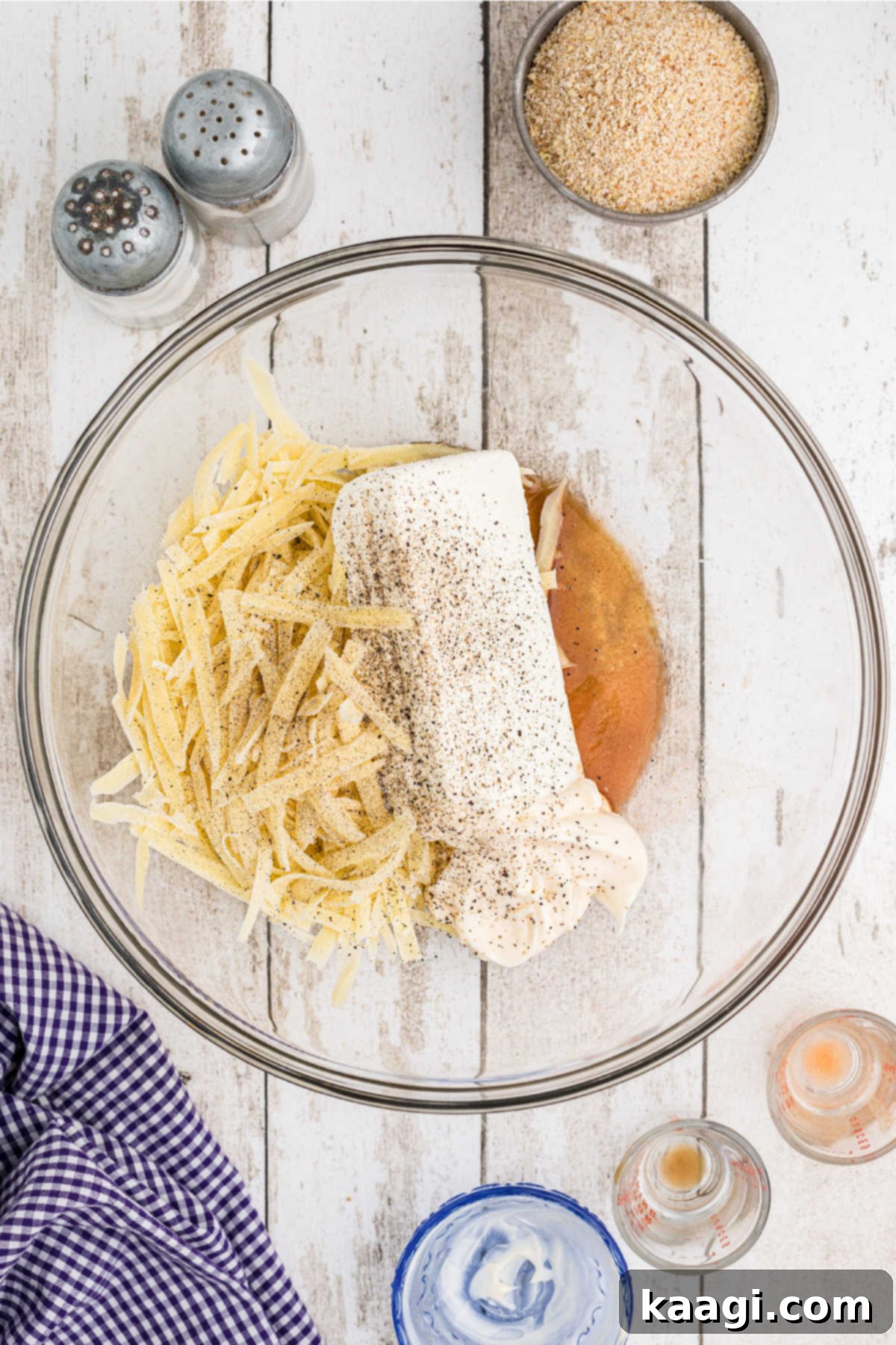 A mixing bowl with grated cheese, cream cheese and seasoning.