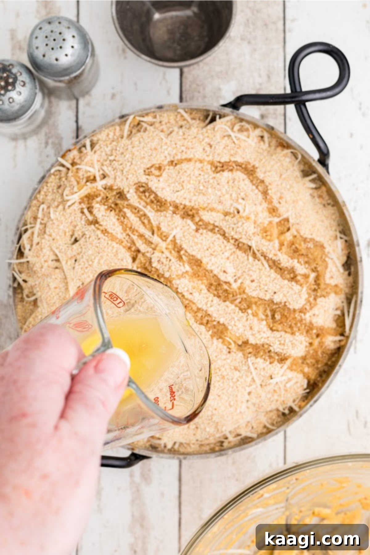 Melted butter being poured over a skillet of crawfish dip.