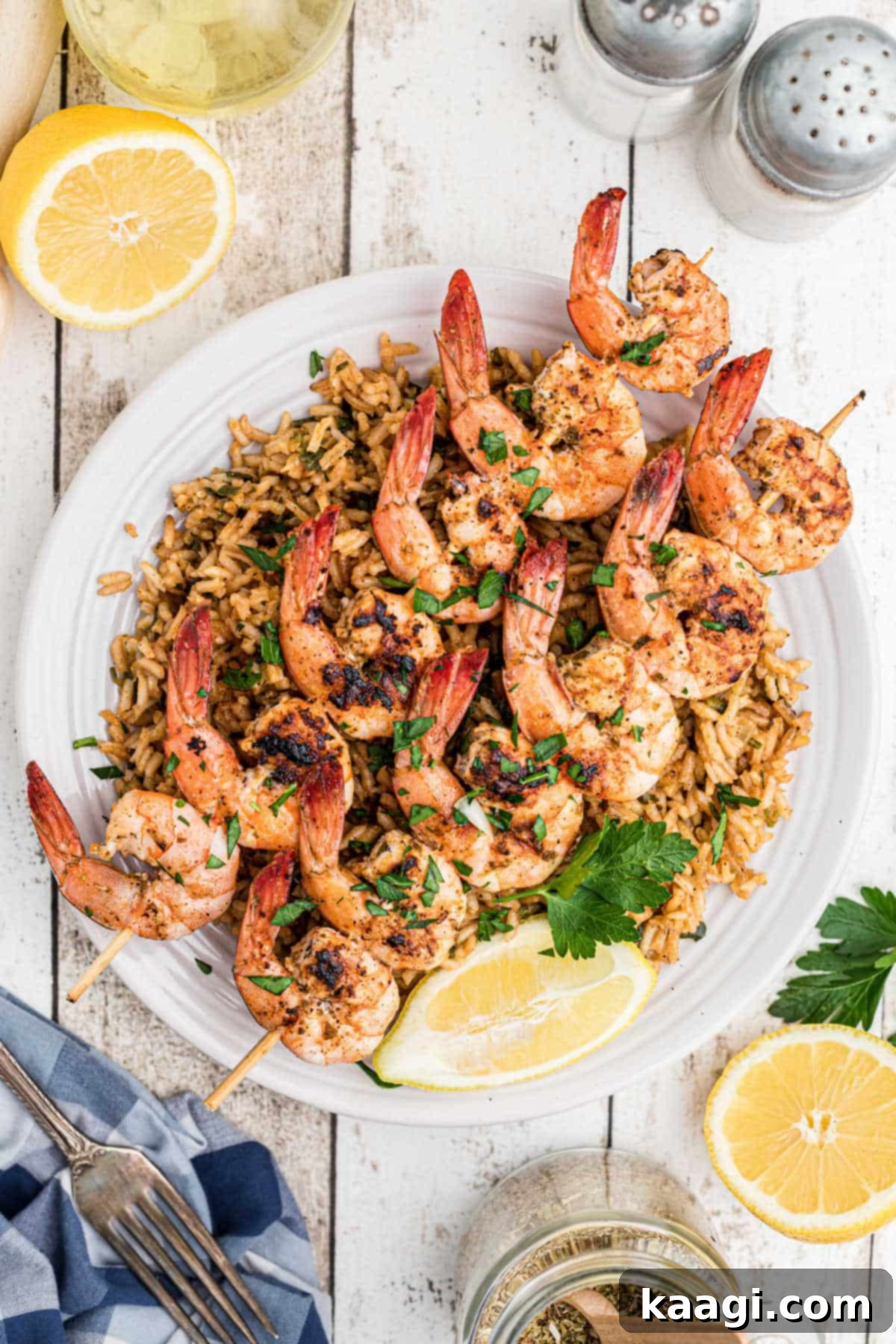Skewers of perfectly seasoned Texas Roadhouse grilled shrimp served on a bed of savory rice, garnished with fresh lemon wedges.