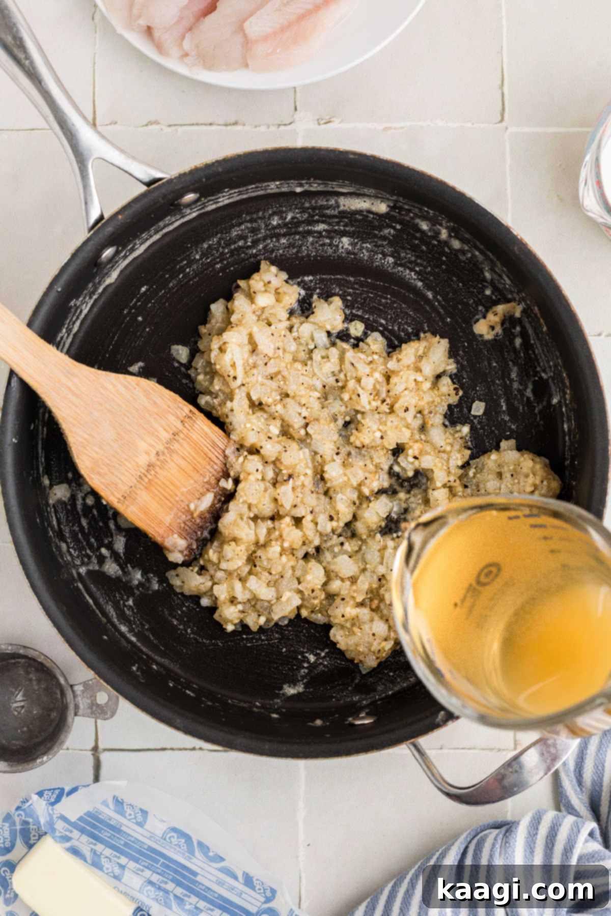 Seafood stock being poured into a large skillet with flour and onions.