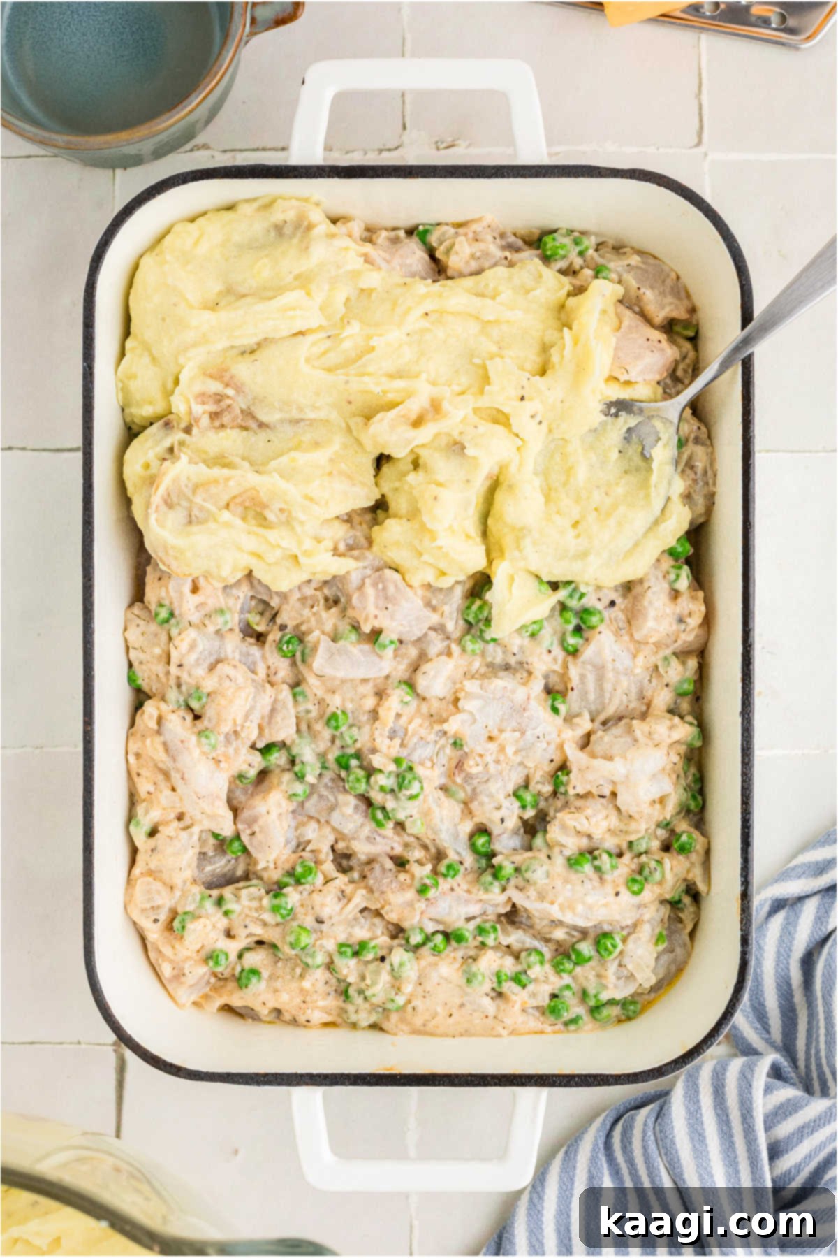 Mashed potatoes being spread on top of fish mixture.