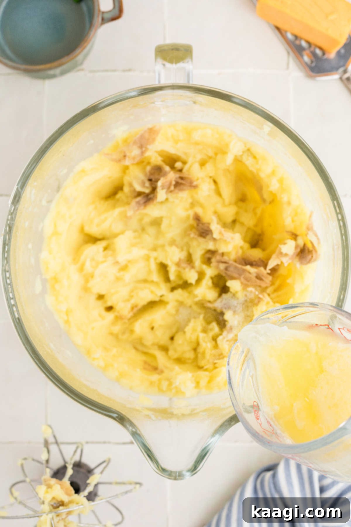 Melted butter and milk being poured into some creamed potatoes.