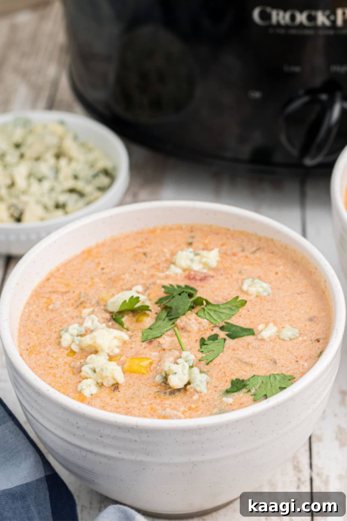 A close-up shot of a steaming bowl of buffalo chicken chili, showcasing its creamy texture and vibrant toppings.