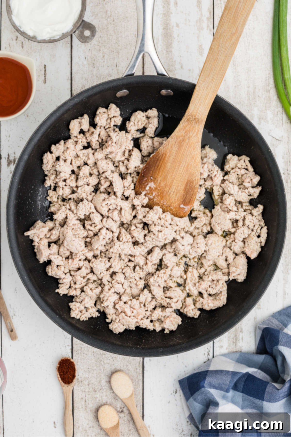 A skillet with ground chicken being browned for the chili.