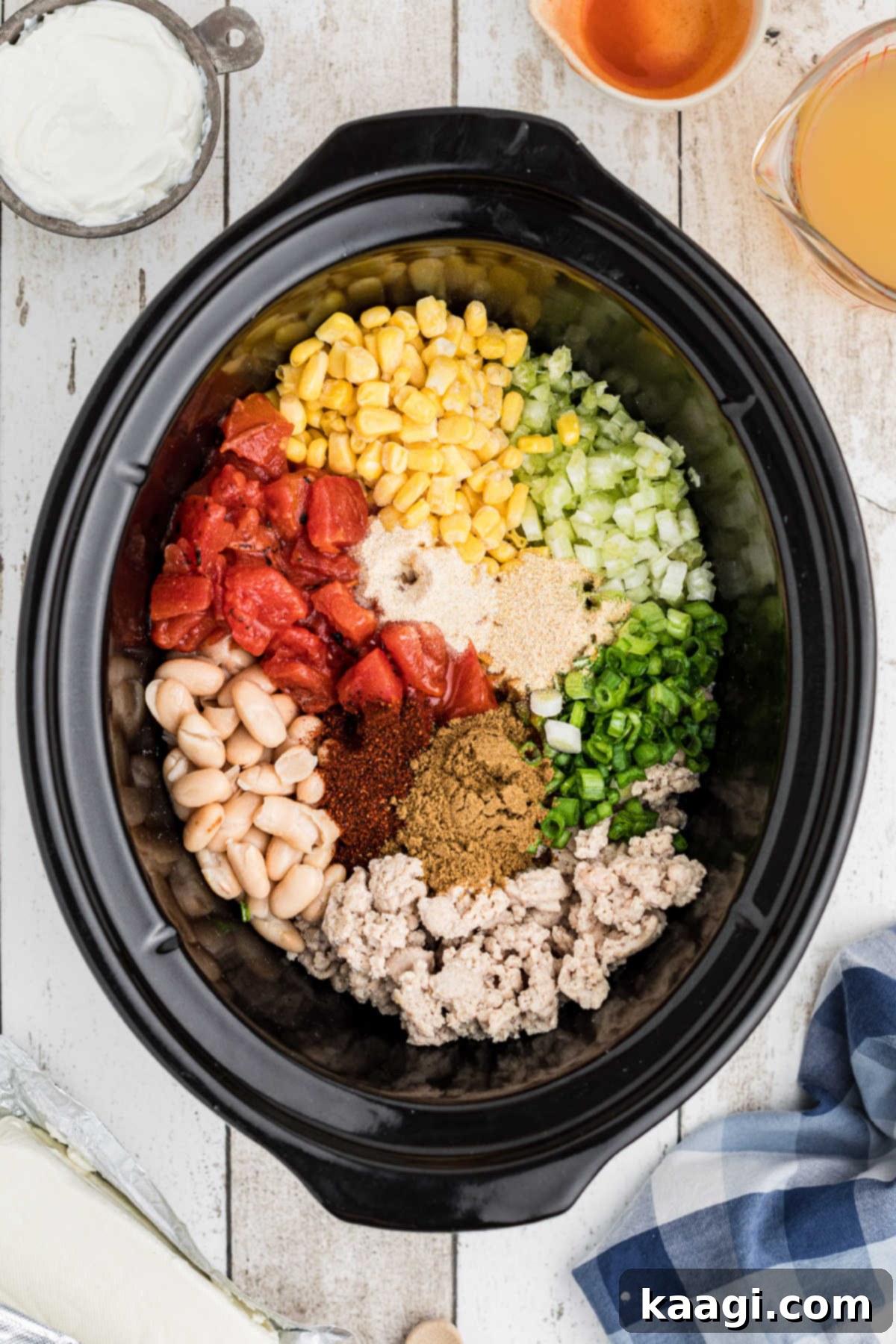 A slow cooker filled with a colorful array of ingredients for buffalo chicken chili, neatly arranged.