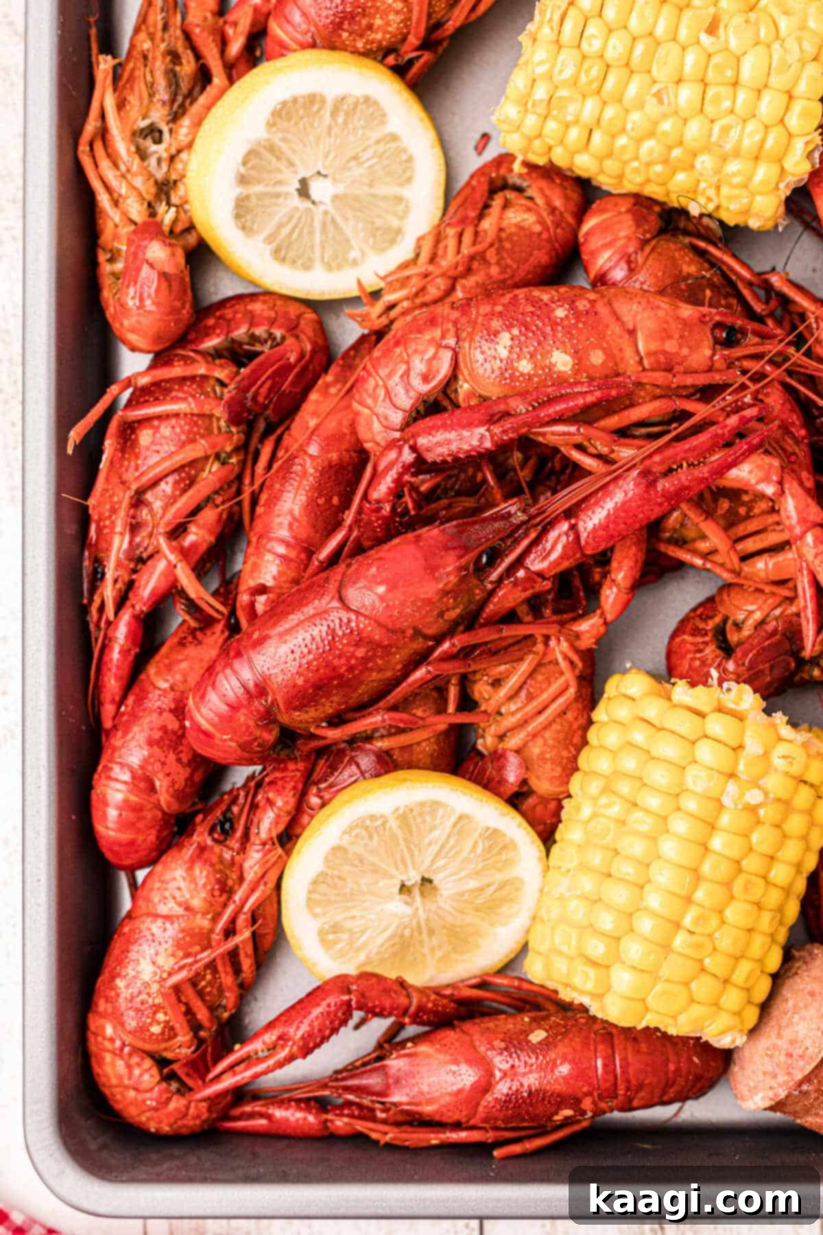 close up of some boiled crawfish on a platter with corn and lemons and sausage
