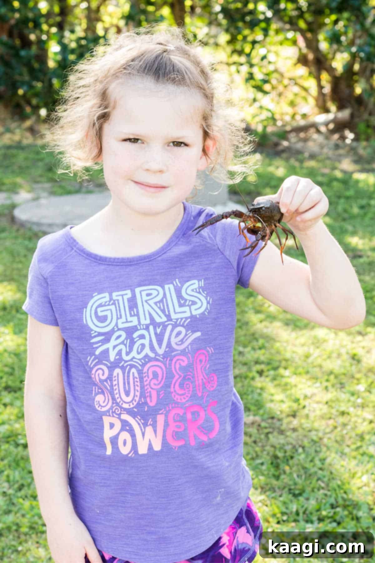 a child holding up a crawfish