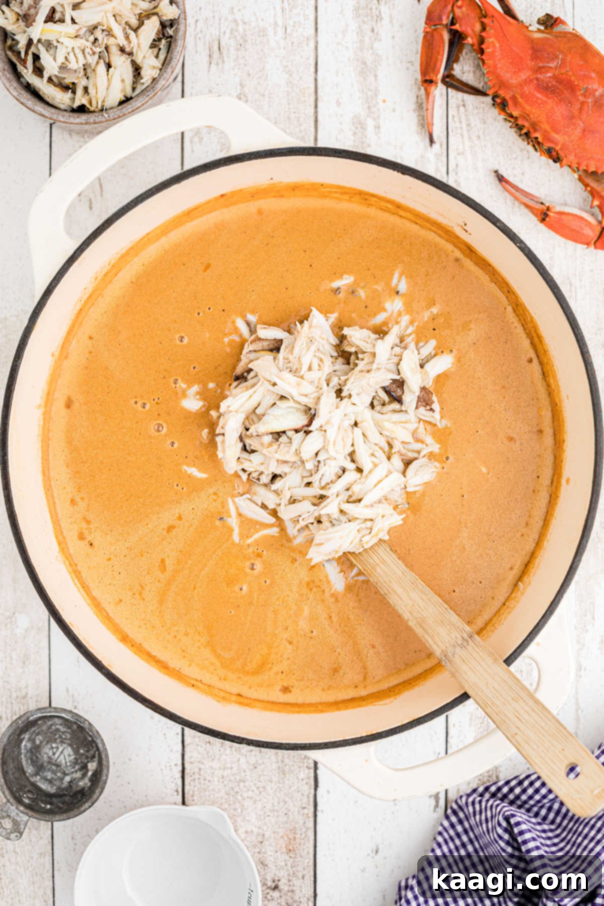 A large pile of crab meat added to a pot with crab soup being made.