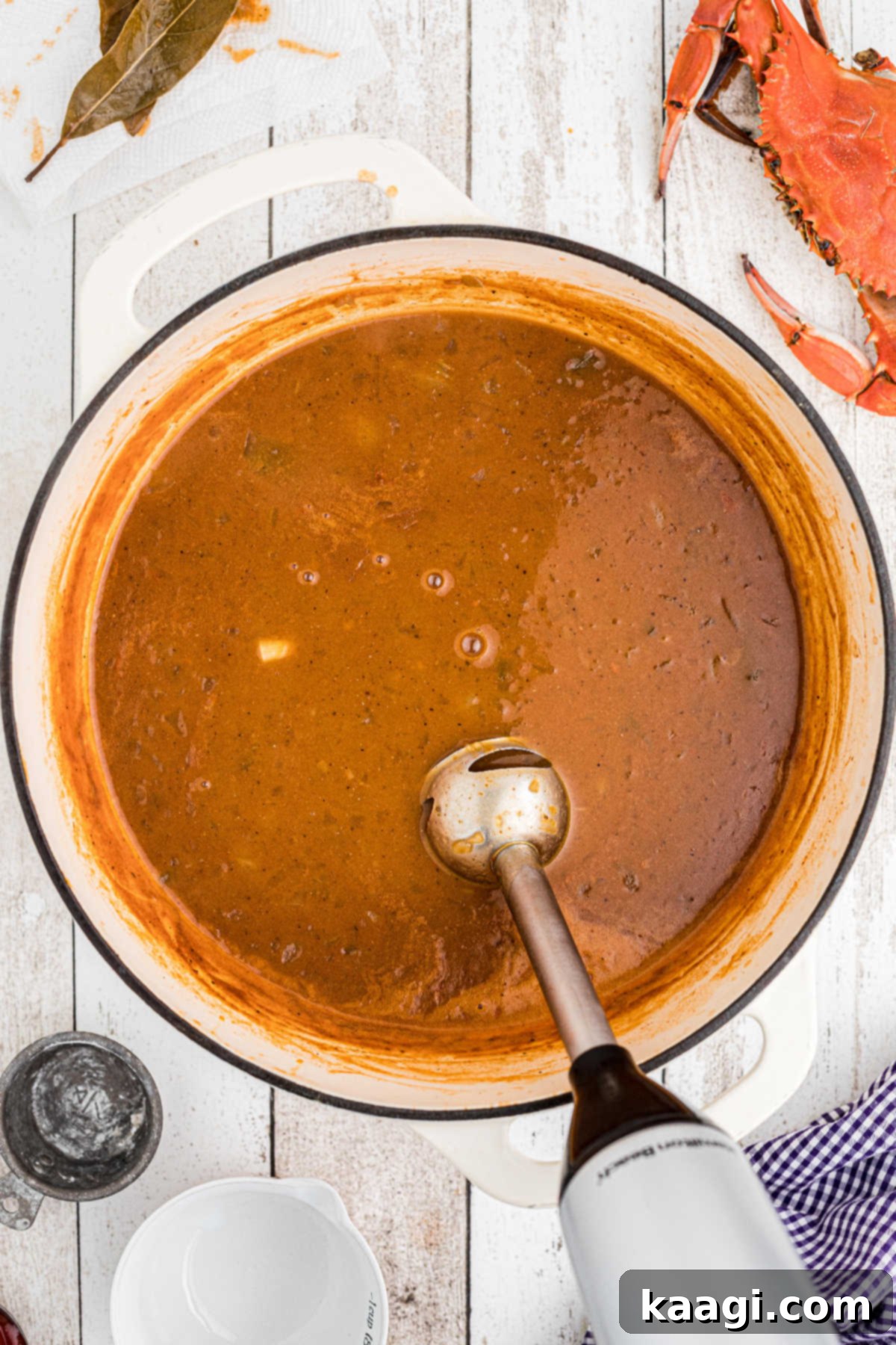 A stick blender being used in a large Dutch oven full of soup.