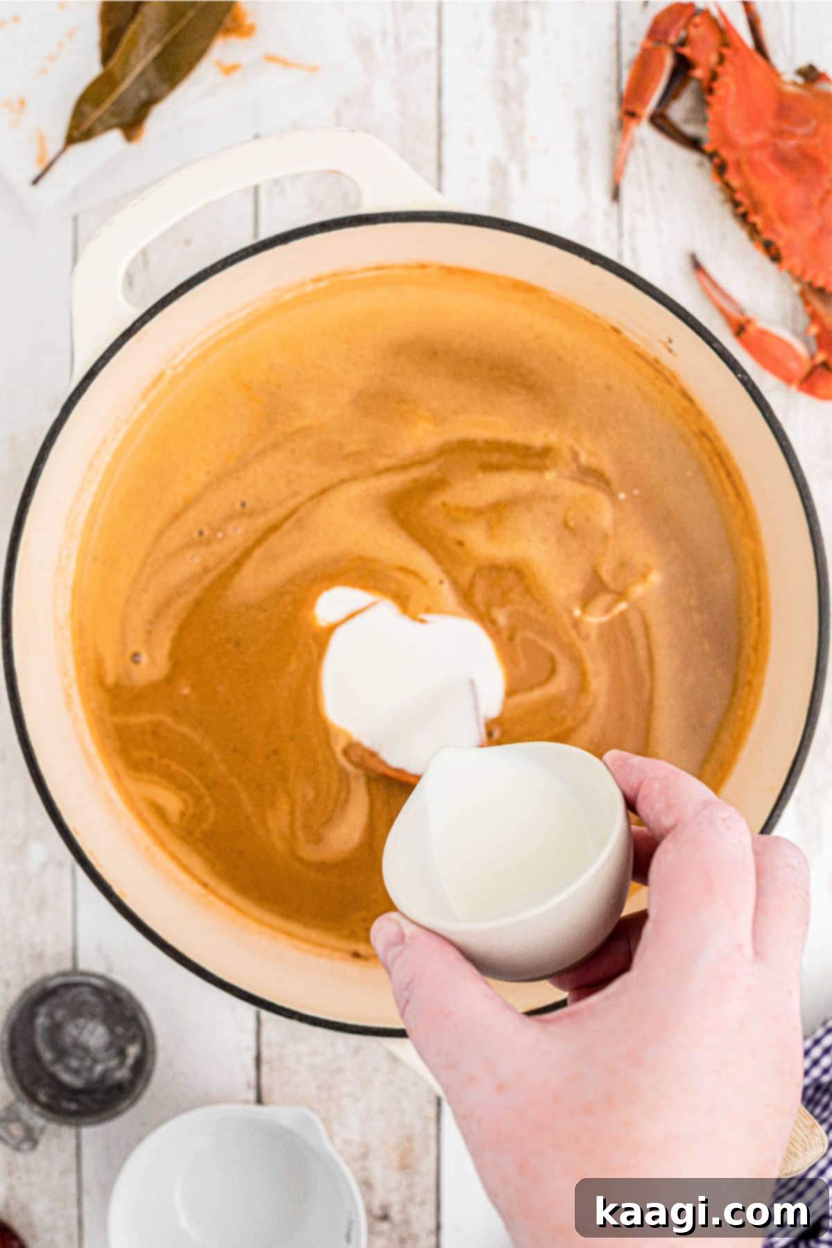 Cream being slowly added to a large soup pot.
