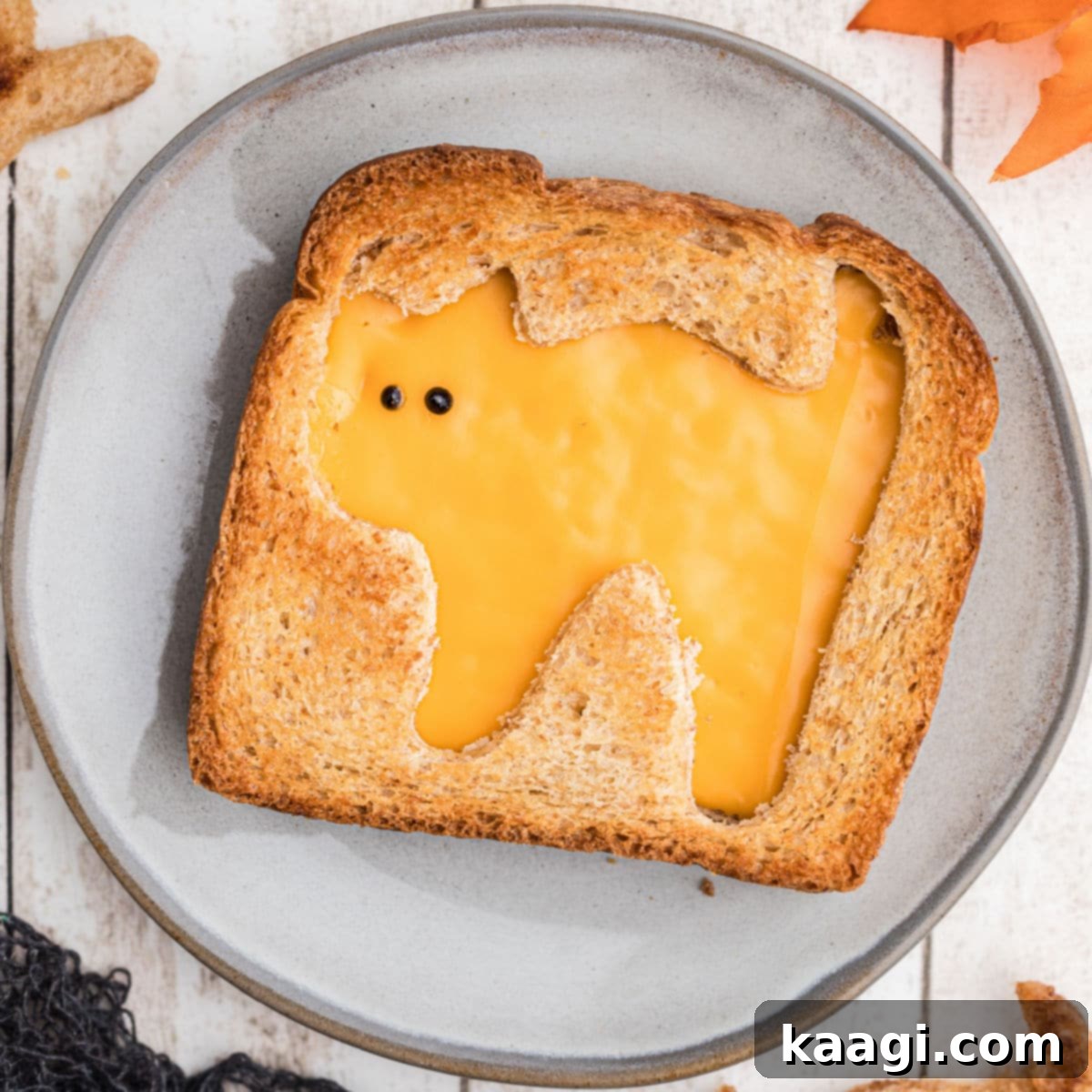 Close-up overhead shot of a Halloween grilled cheese sandwich with a cat silhouette cut out, sitting on a spooky themed plate, making it an ideal Halloween snack for kids.