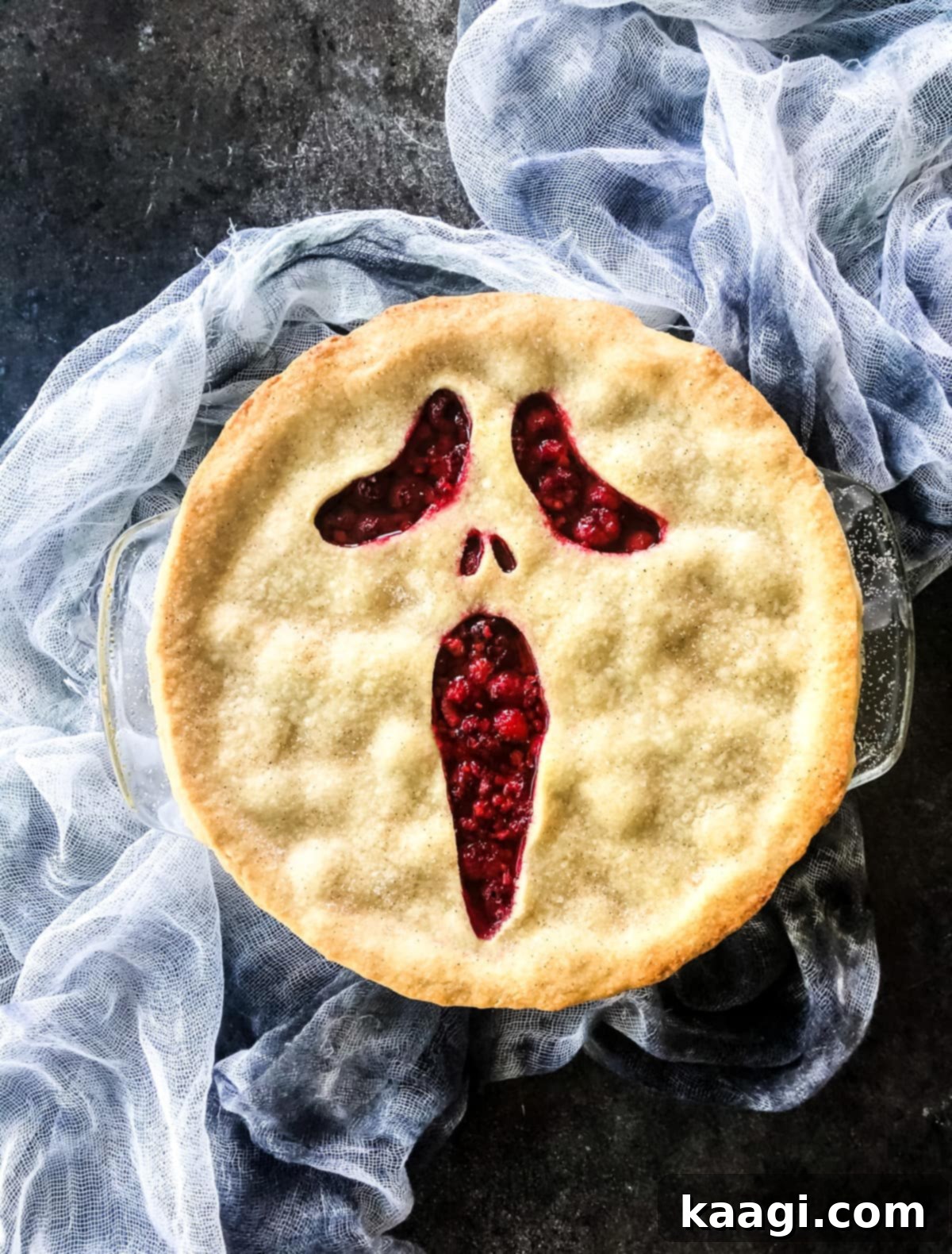 A Halloween-themed pie with a raspberry filling, featuring a pastry crust cut to resemble the iconic 'Scream' face.