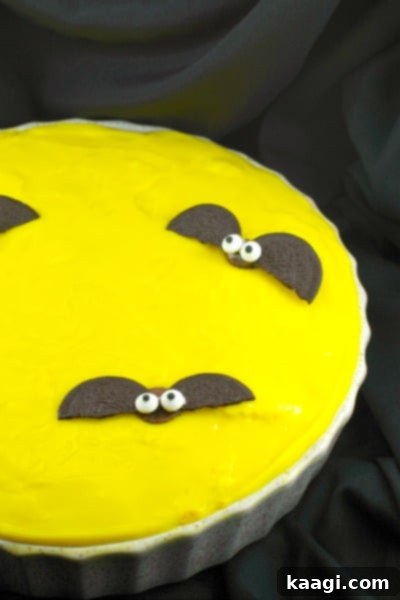 A vibrant yellow Halloween pie featuring adorable bat decorations on top.