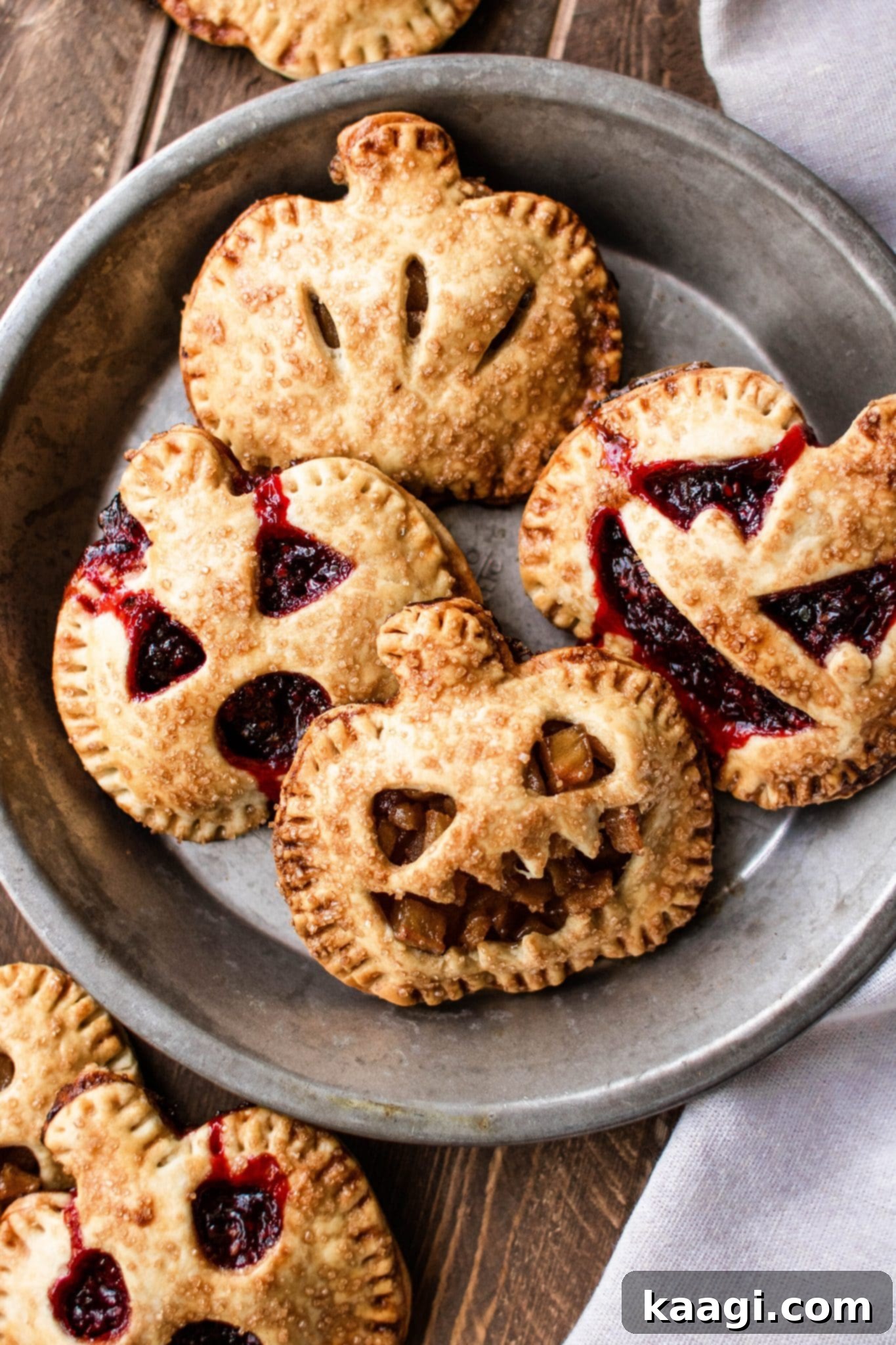 Adorable hand pies skillfully shaped like grinning jack-o'-lanterns, perfect for Halloween treats.
