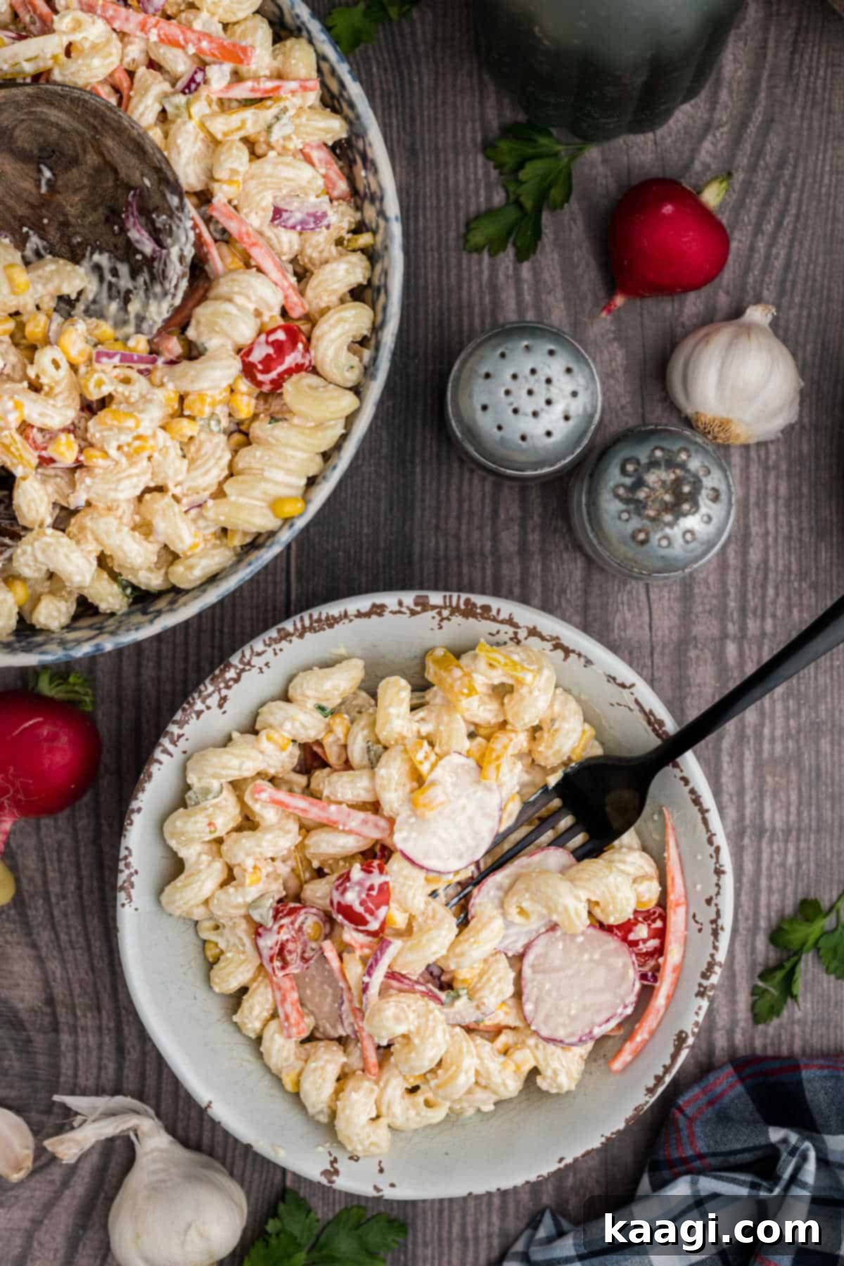 A dish of late summer pasta salad with a fork digging in, showing the rich texture and colorful ingredients.