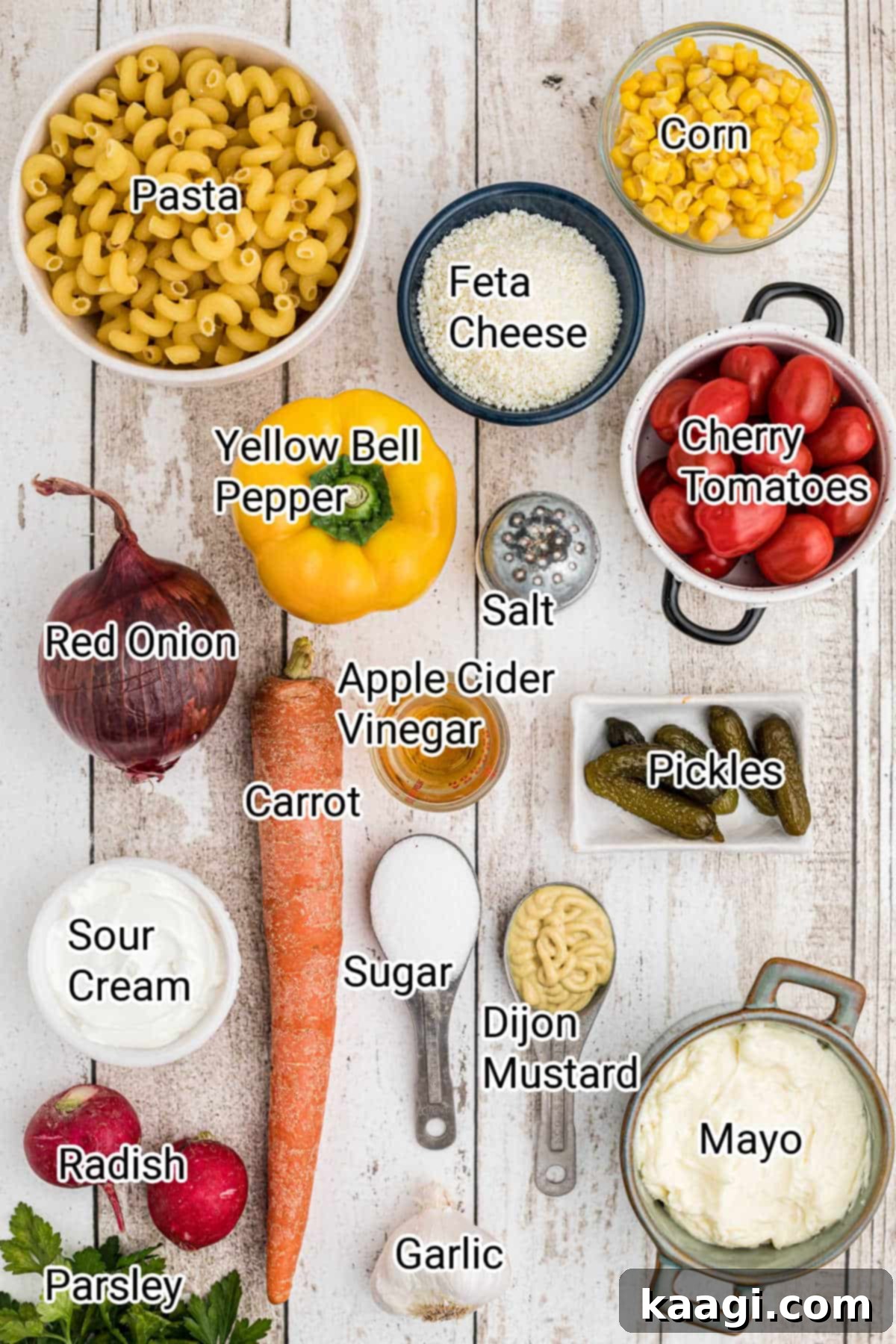 A beautiful flat lay image of all the fresh ingredients for a summer pasta salad, artfully arranged on a wooden surface.