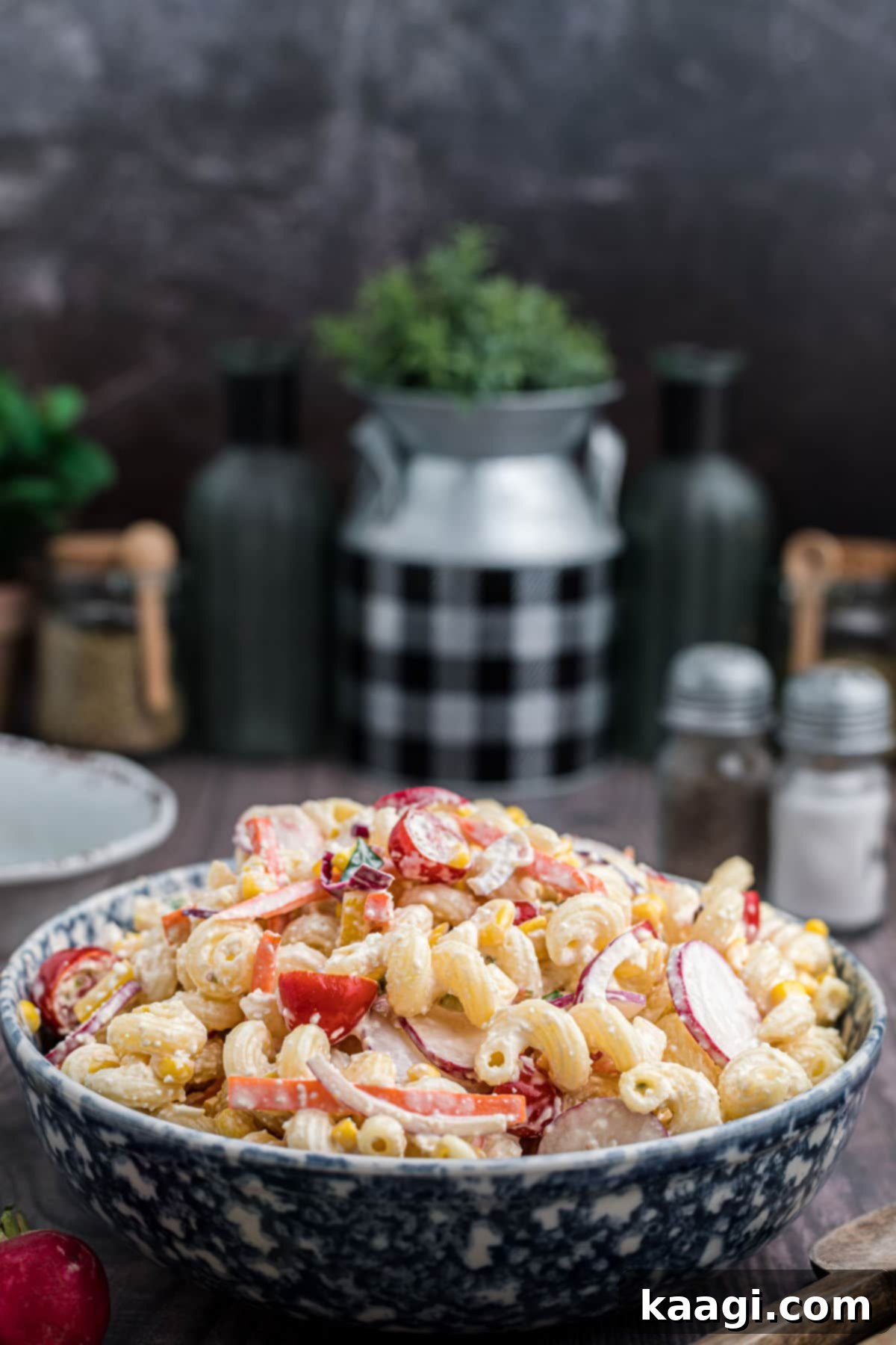 A beautiful side view of a large bowl of Late Summer Pasta Salad, showing layers of pasta, vegetables, and creamy dressing.