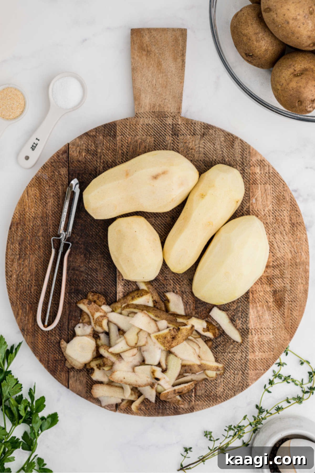 Pressure-Perfect Crispy Spuds 4 Potatoes on a chopping board, peeled and ready to be cut.