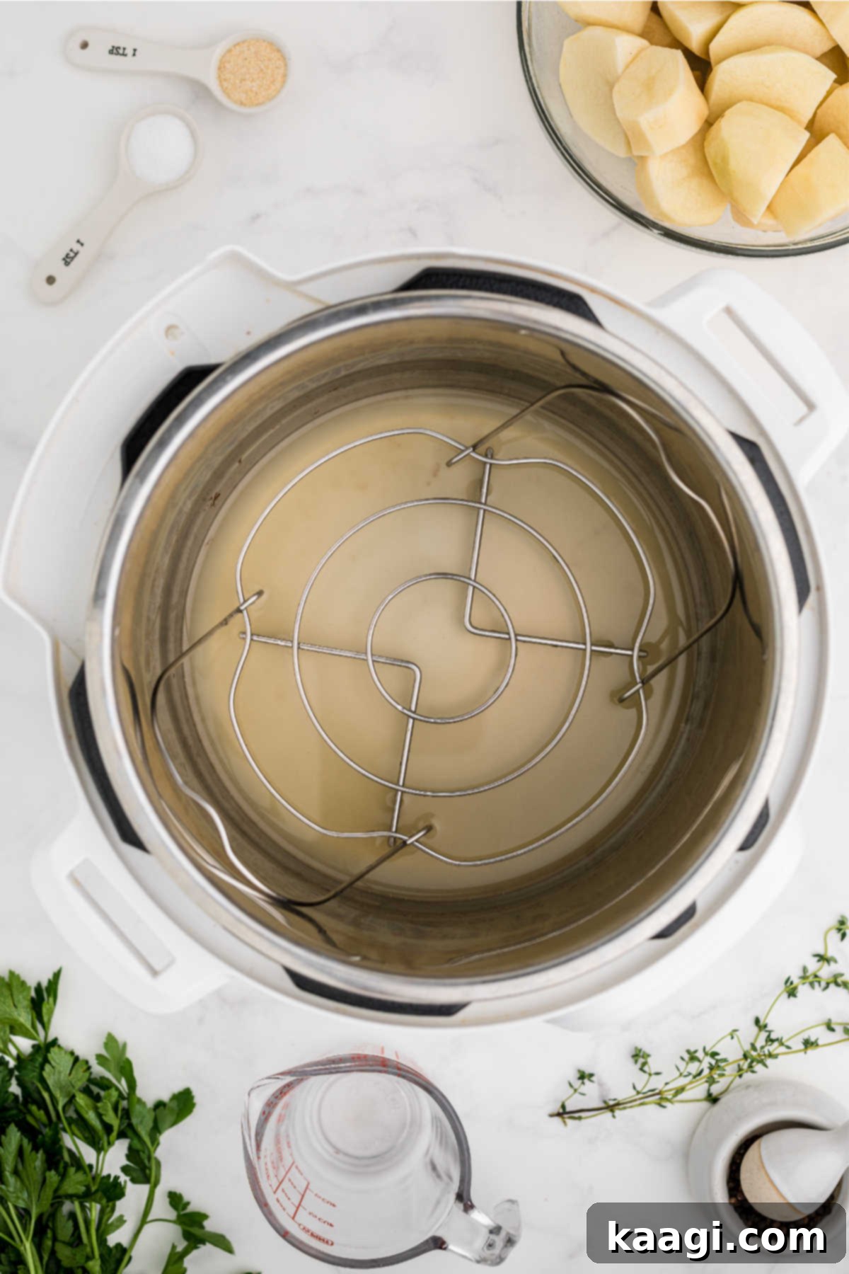 Pressure-Perfect Crispy Spuds 6 An Instant Pot with a basket and chicken broth in the bottom.