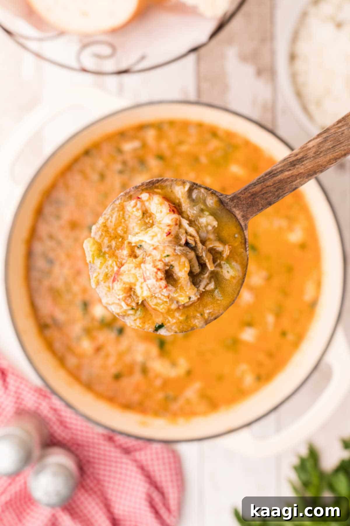 A spoon full of crawfish etouffee over a pot in the background