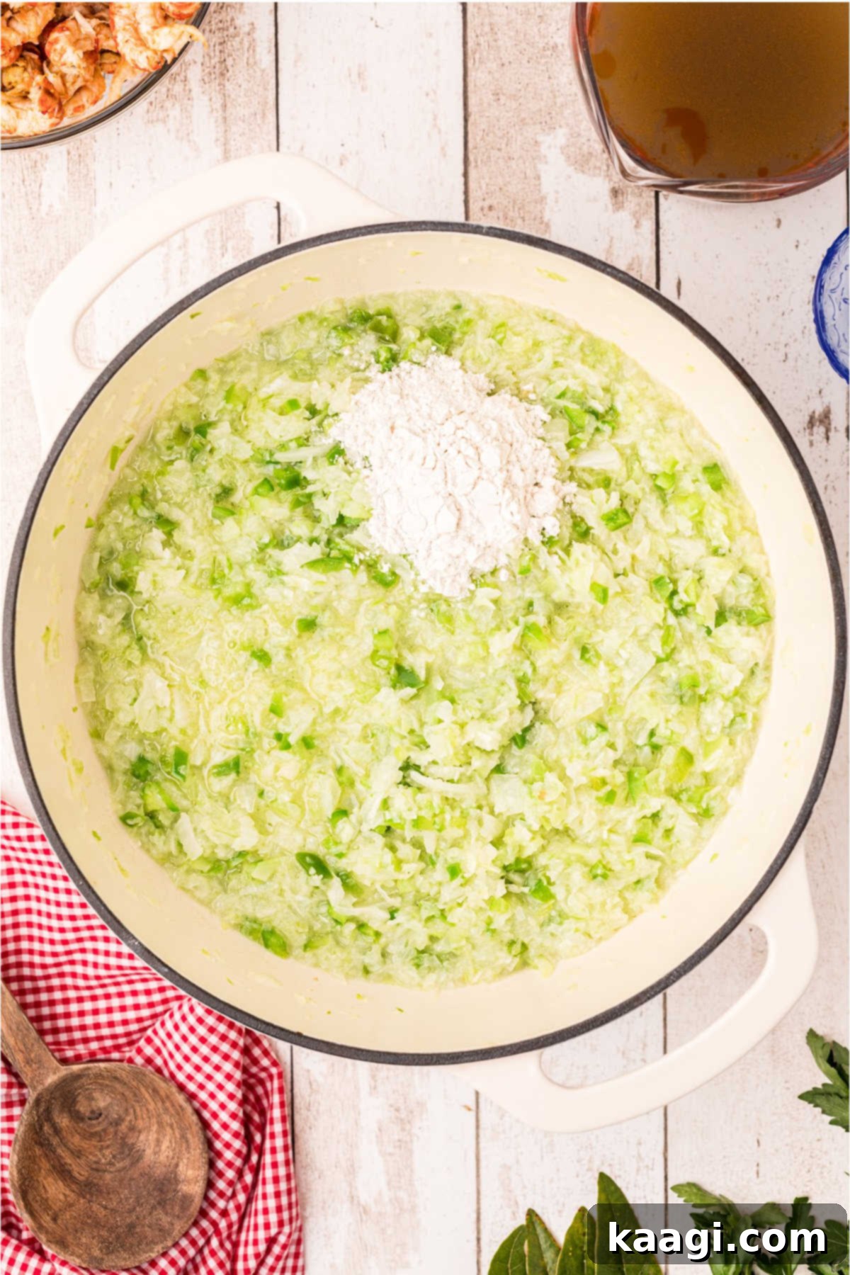 A spoon of flour has been added to a large Dutch oven with onions, bell pepper and celery.