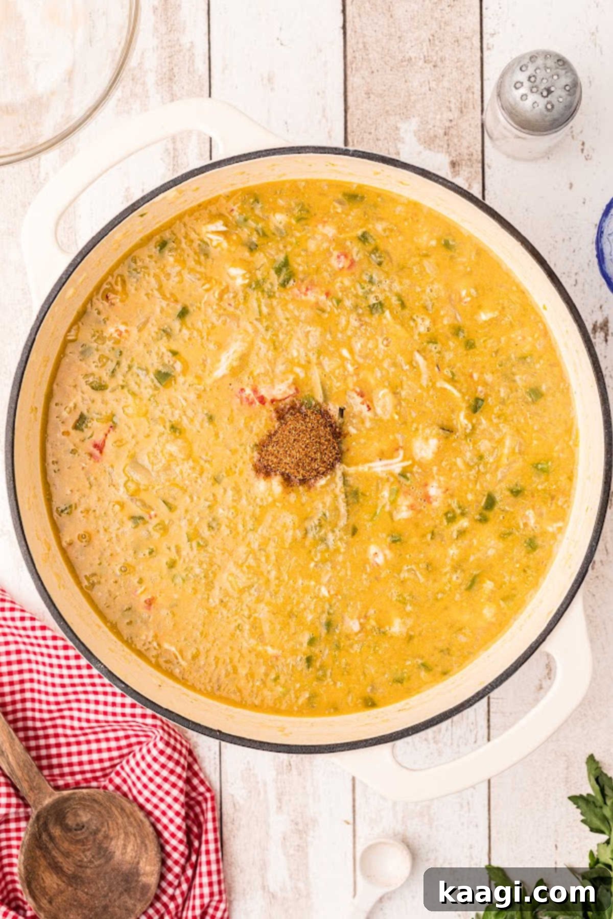 Seasoning added to a large Dutch oven filled with crawfish etouffee.