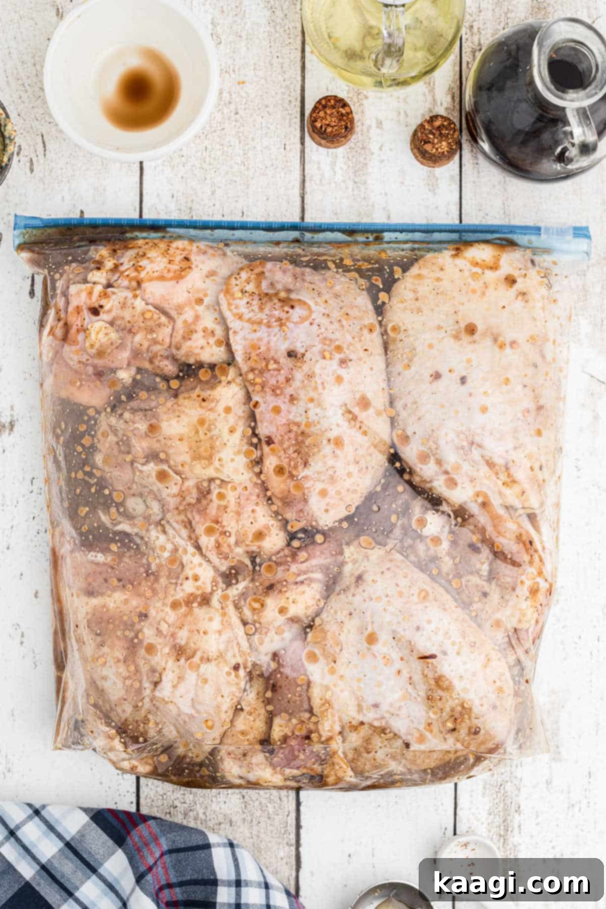 A resealable plastic bag containing chicken thighs fully submerged in a rich, savory marinade, ready for refrigeration.