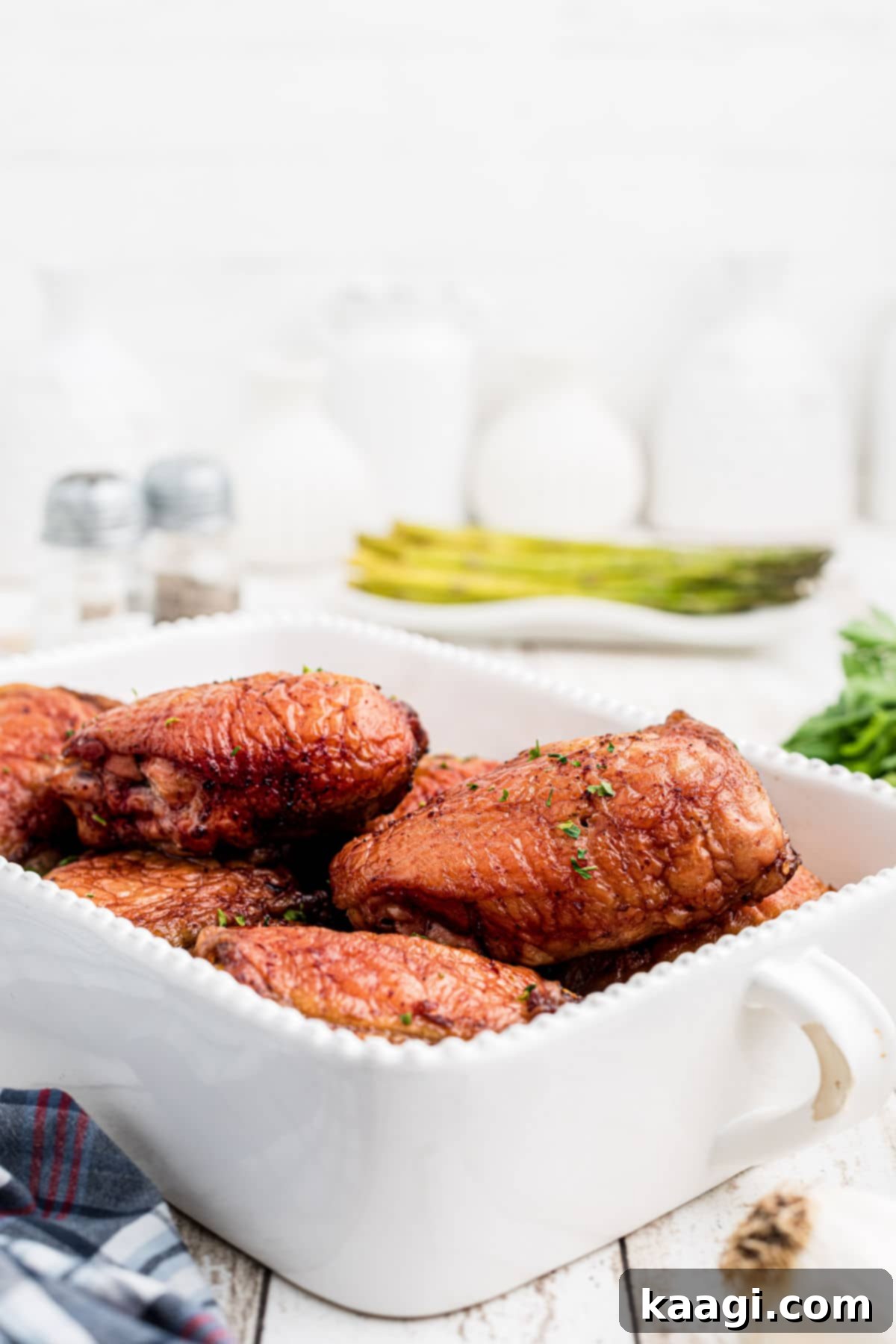 A perfectly arranged dish featuring succulent smoked chicken thighs, beautifully cut to reveal tender meat, accompanied by fresh asparagus spears.