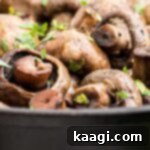 Wood-Kissed Mushrooms 7 Close up of some smoked mushrooms in a cast iron pot, garnished with fresh parsley.