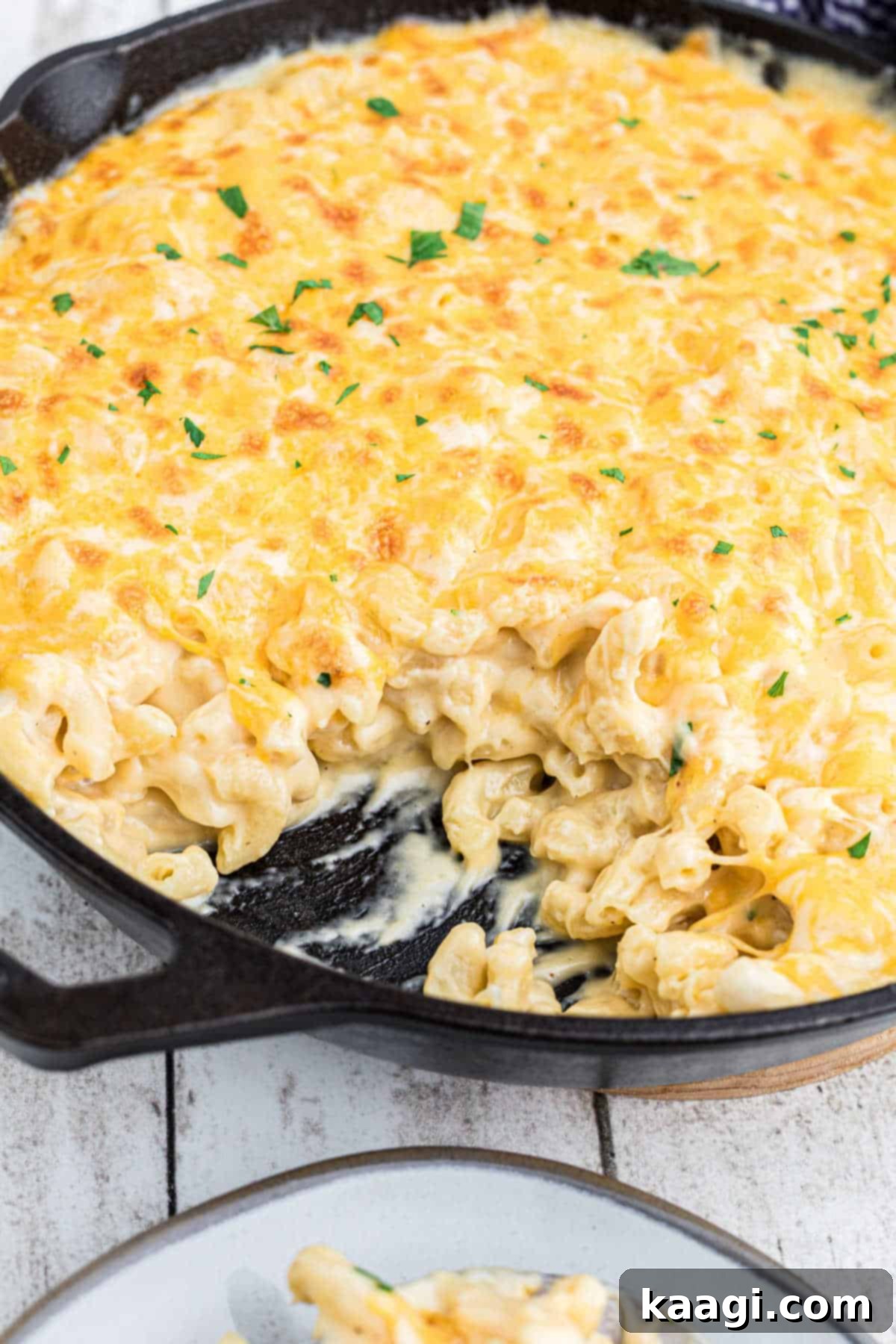 close up of mac and cheese in a cast iron skillet with some missing.