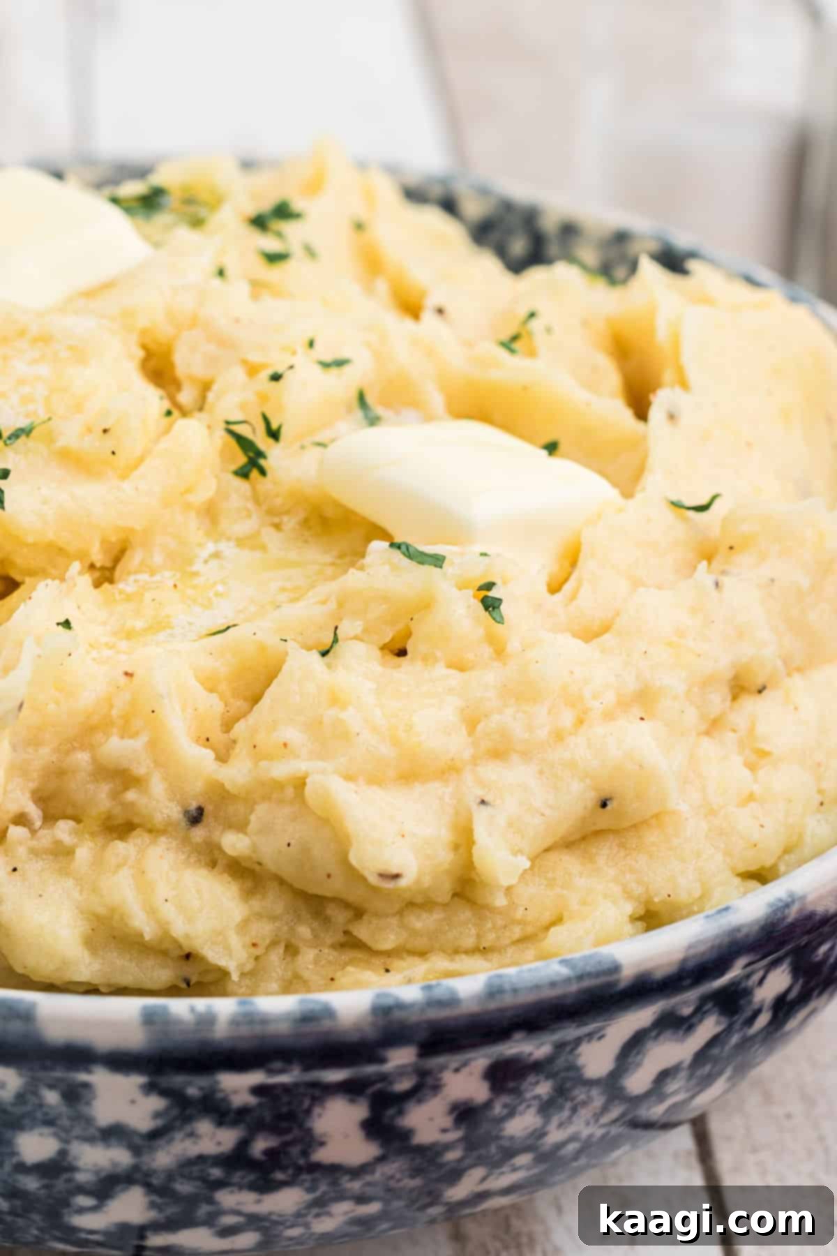 A close-up view of a large bowl of homemade copycat Popeyes mashed potatoes with a swirl of melting butter, ready to be served.