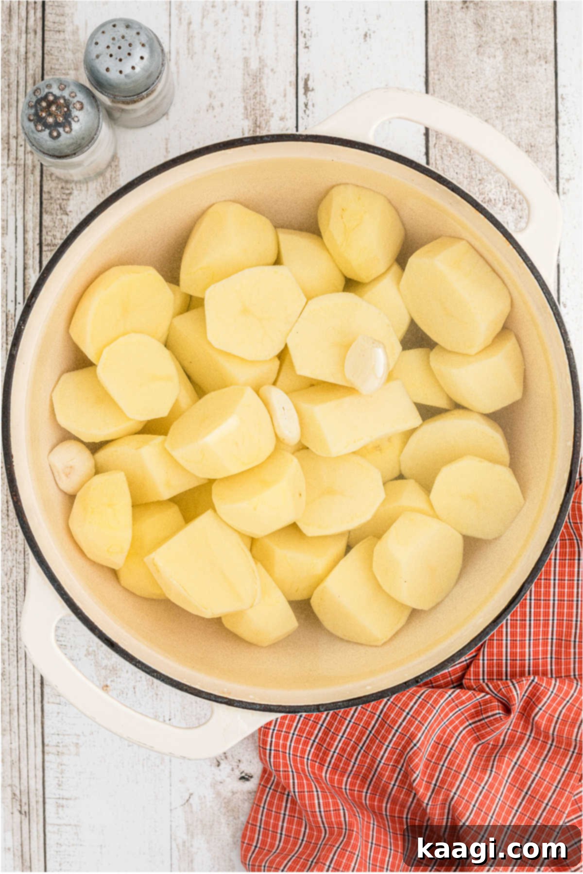 Peeled and chopped potatoes and garlic cloves in a large Dutch oven pot, ready for boiling.