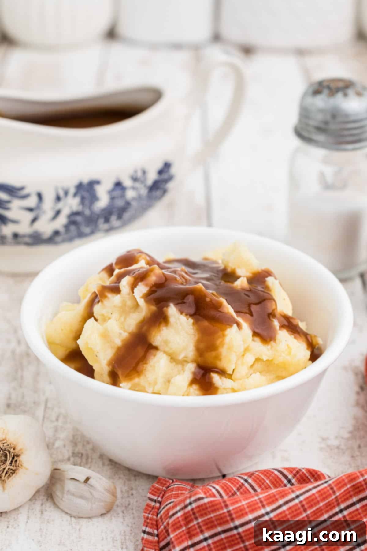 A bowl of creamy mashed potatoes with a generous drizzle of savory brown gravy on top.
