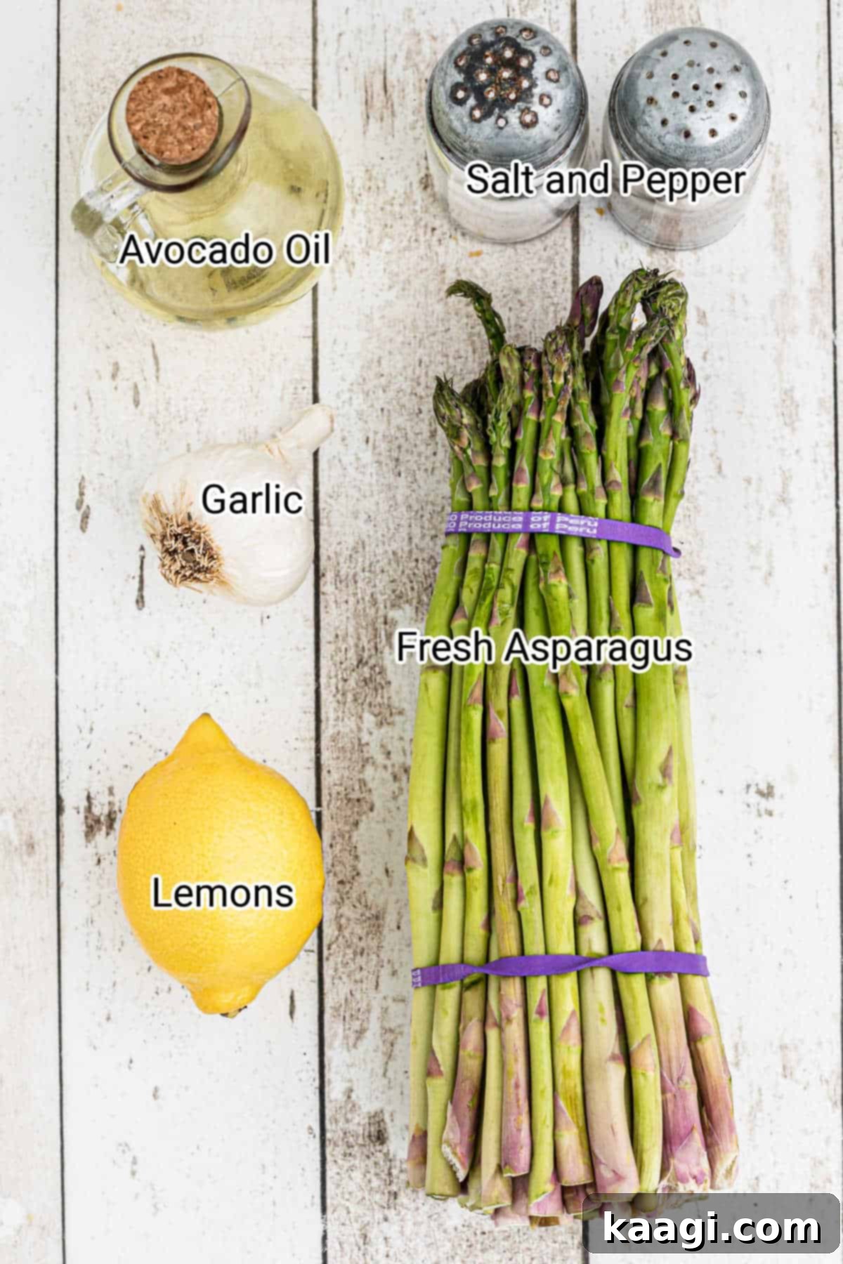 A vibrant flat lay showcasing the simple ingredients required for smoked asparagus: fresh asparagus, avocado oil, garlic cloves, salt, pepper, and bright yellow lemons.