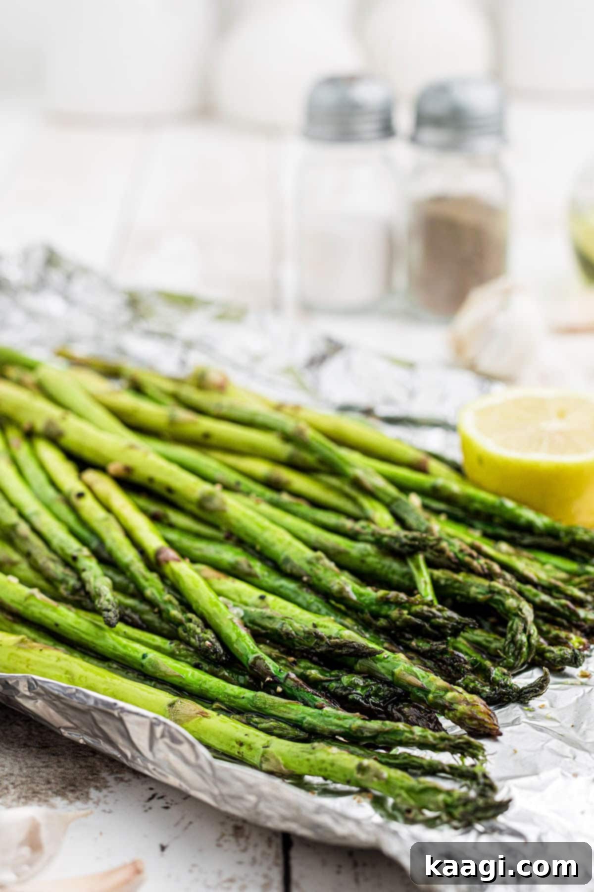 Close-up overhead shot of glistening smoked asparagus spears, artfully arranged with fresh lemon slices, highlighting its appeal as the perfect summer side dish.