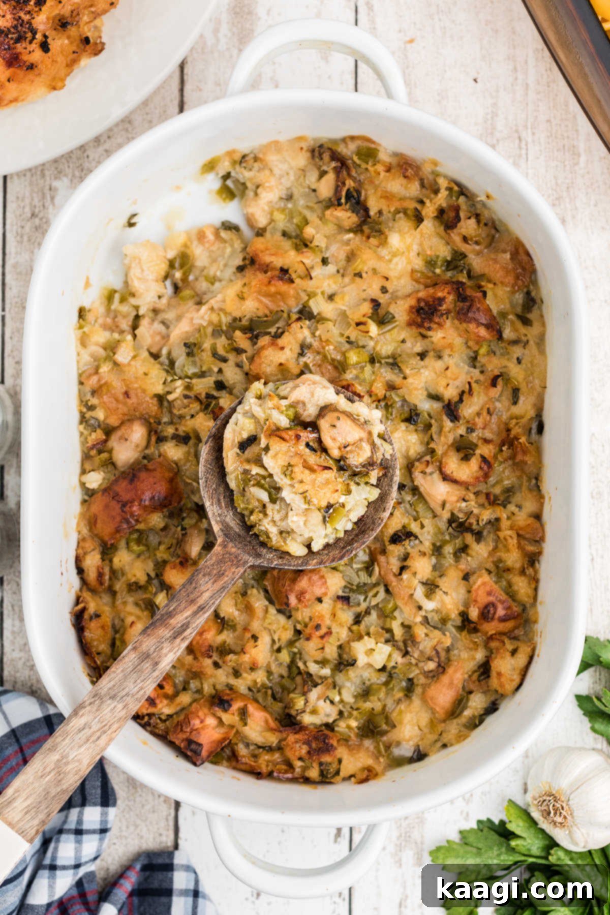 A freshly baked oyster dressing, golden brown and bubbling, with a serving spoon scooping out a portion.