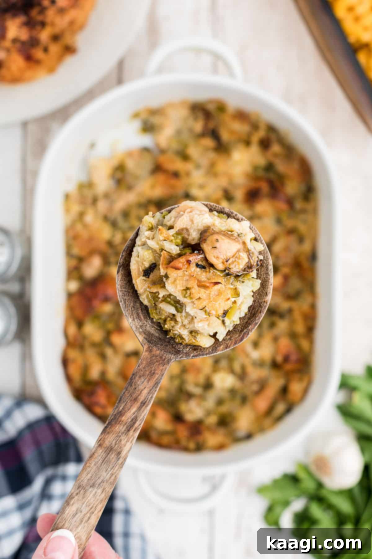 A close-up of a baked oyster dressing in a casserole dish, with a spoon scooping out a serving, showcasing its rich texture.