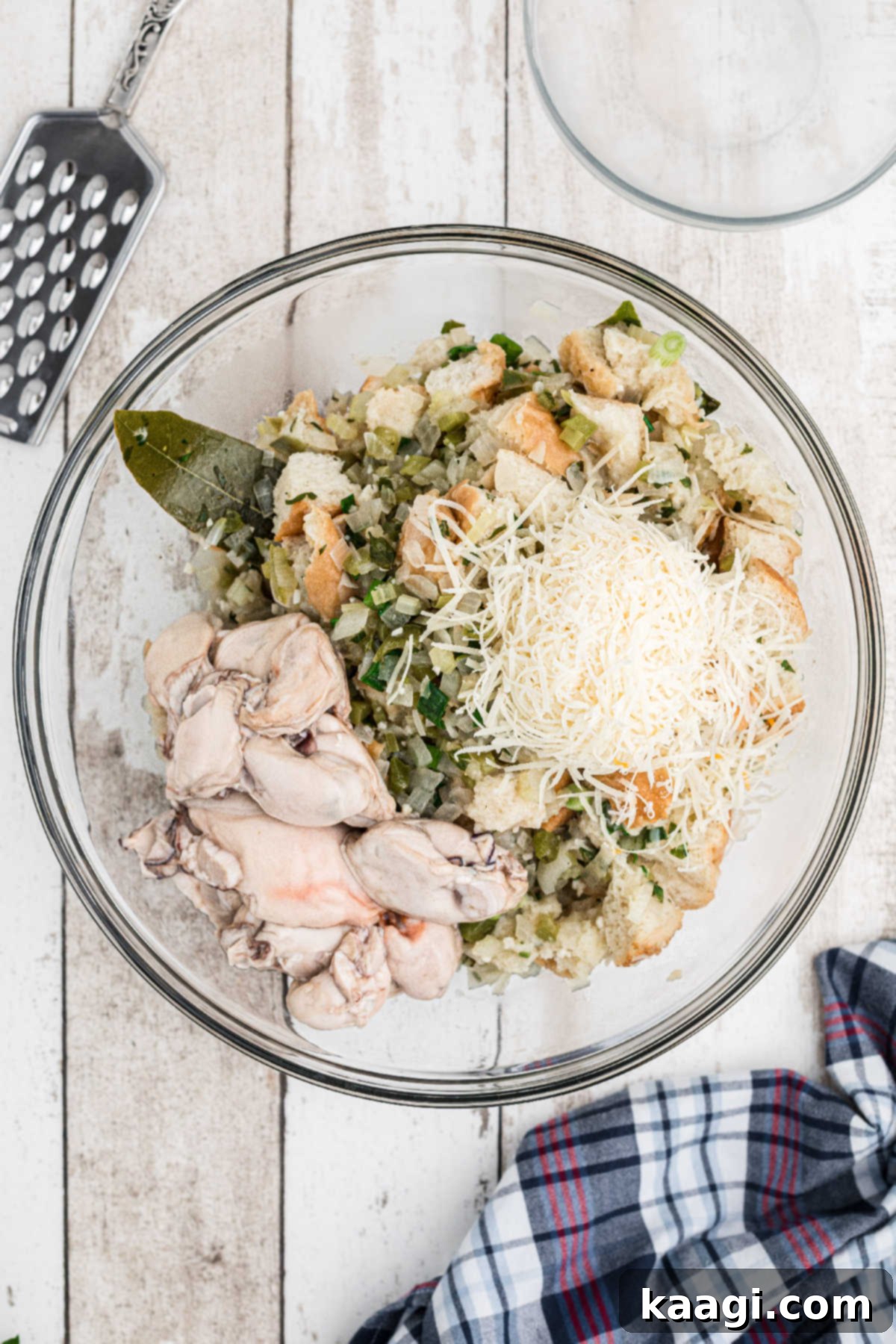 A large mixing bowl containing the dressing base, fresh whole oysters, and grated Parmesan cheese, ready for mixing.