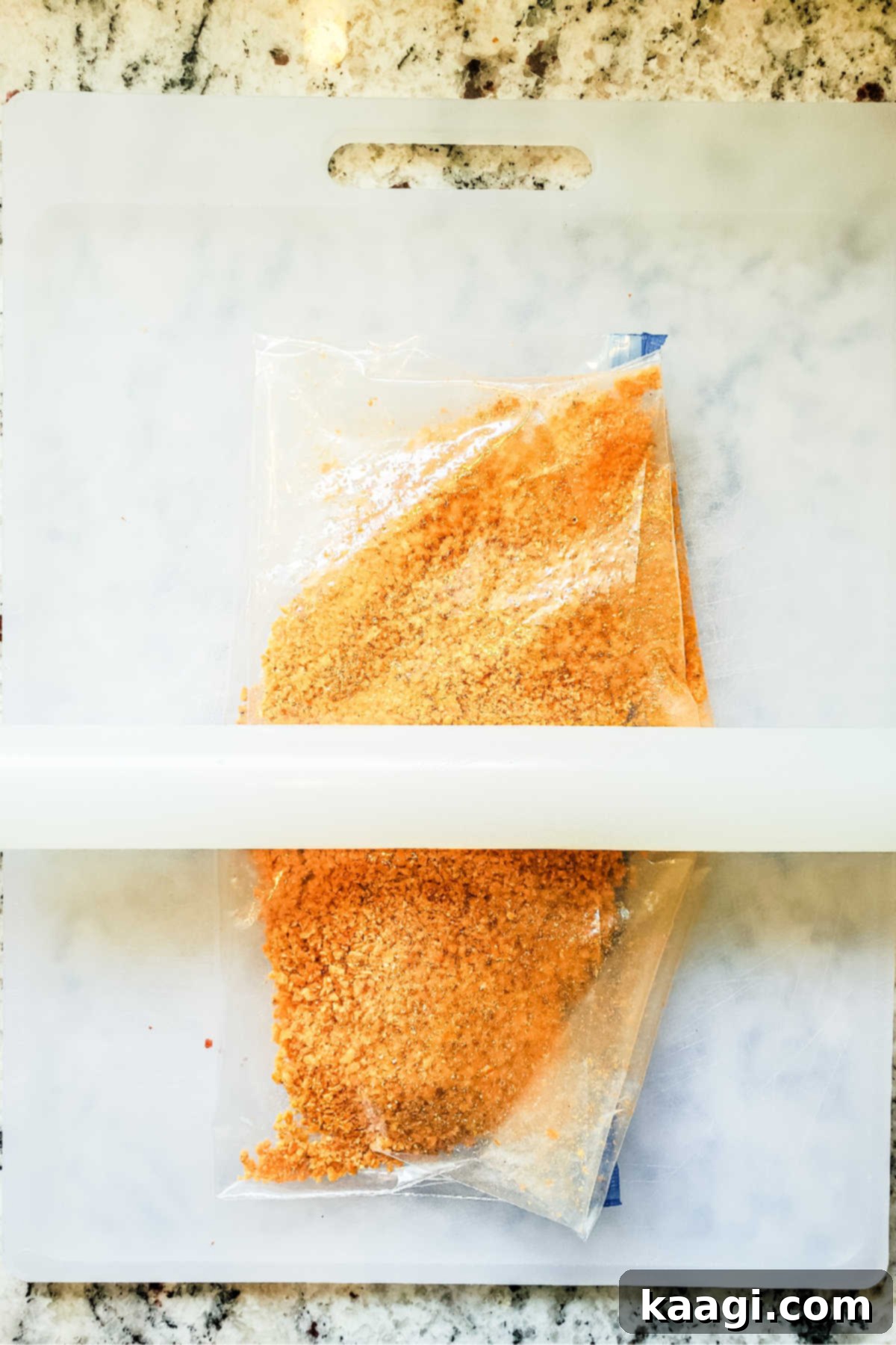 Crispy Air Fryer Mac & Cheese Poppers 5 A resealable plastic bag filled with bright orange Dorito chips, being crushed with a rolling pin to create fine crumbs for coating.