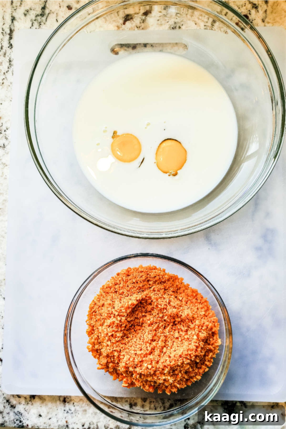 Crispy Air Fryer Mac & Cheese Poppers 6 Two mixing bowls on a counter: one holds a whisked egg and milk mixture for the egg wash, and the other contains crushed Dorito crumbs for the coating.