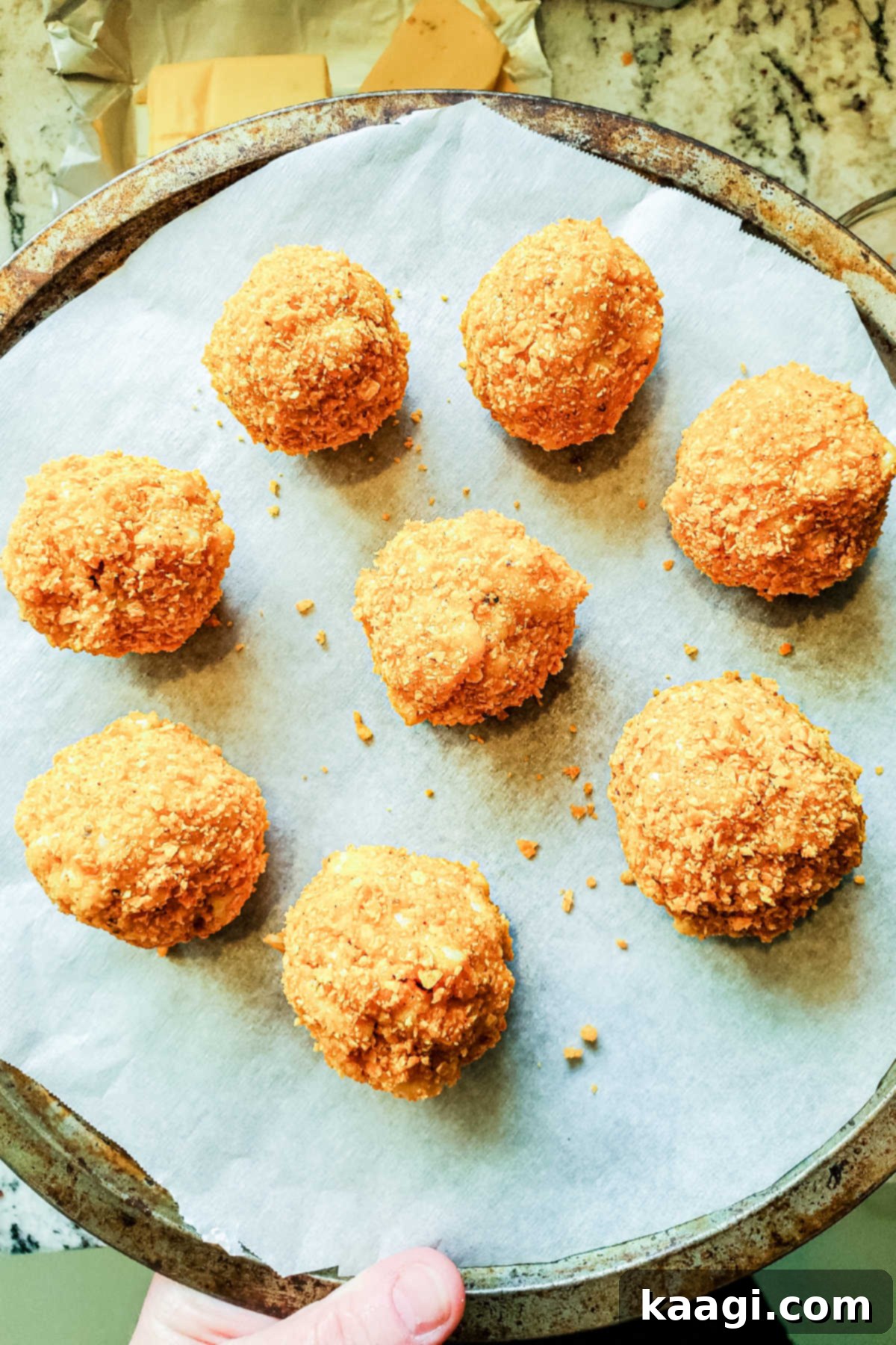 Crispy Air Fryer Mac & Cheese Poppers 7 Several perfectly rolled and coated mac and cheese bites arranged on a baking sheet, ready for freezing and then air frying.