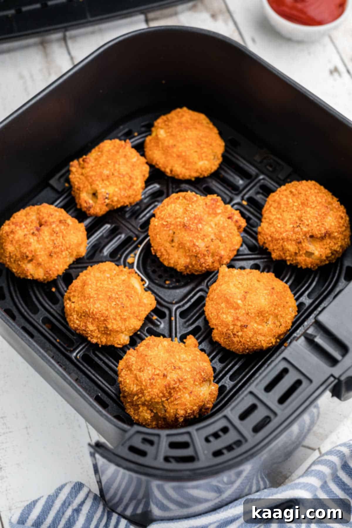 Crispy Air Fryer Mac & Cheese Poppers 8 An air fryer basket generously filled with golden-brown, crispy Air Fryer Mac and Cheese Bites, perfectly cooked and ready to be served.